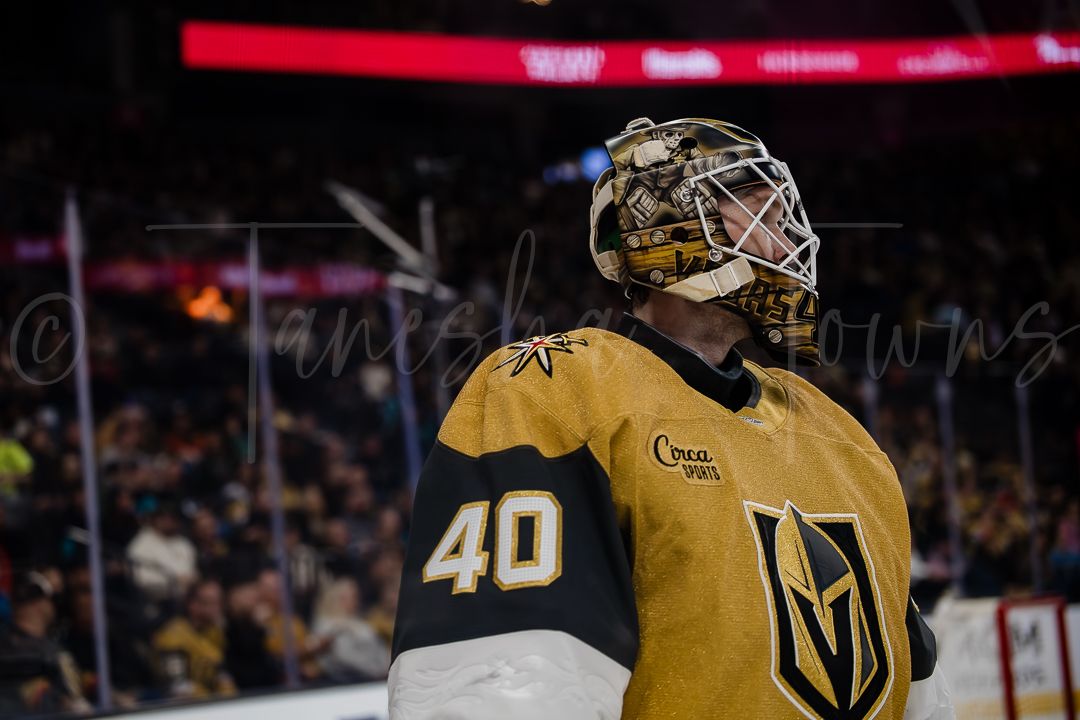 NHL goalie in Vegas Golden Knights uniform stretches to make a dramatic save during game action.