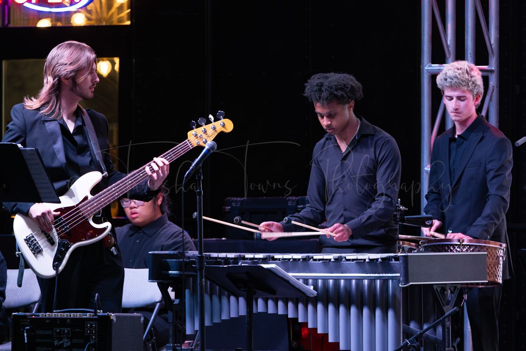 Jazz ensemble performs on stage with various instruments including piano and percussion.