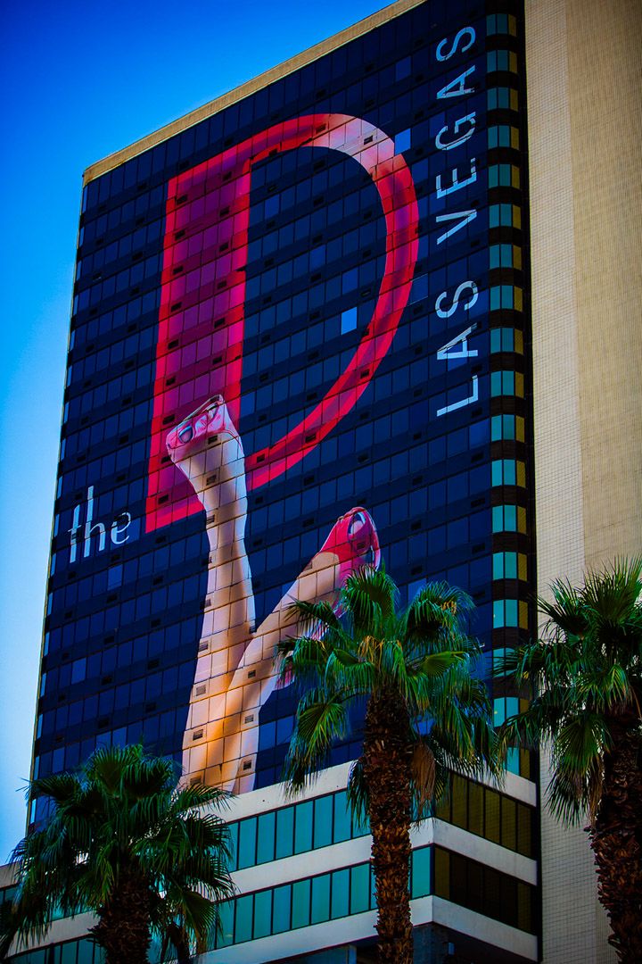 Large hotel building with colorful illuminated artwork displayed across its facade at dusk.