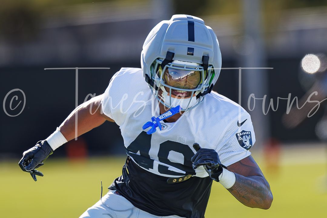 Raiders player number 48 in white uniform runs a route during NFL training camp practice.