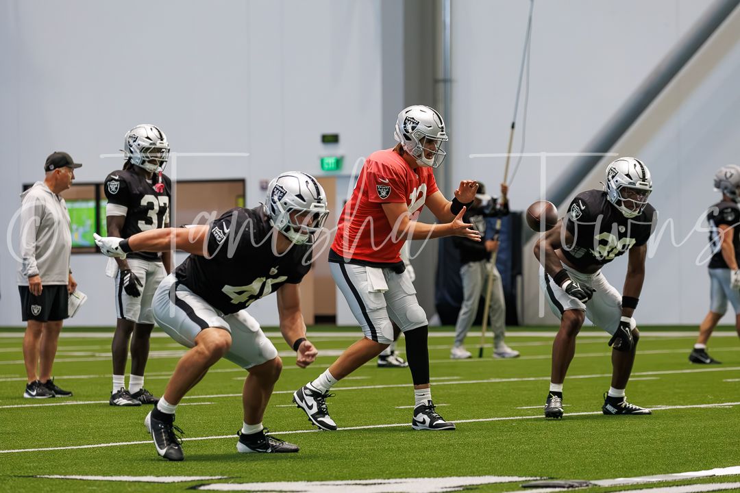 Las Vegas Raiders players practice drills indoors at training camp facility.
