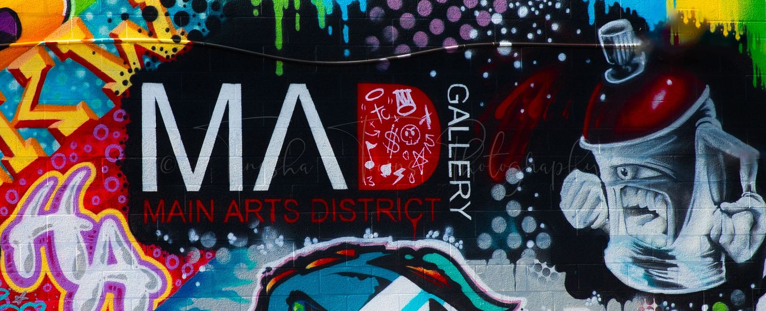 Urban wall art featuring mixed media graffiti with text and graphic elements in dark tones.