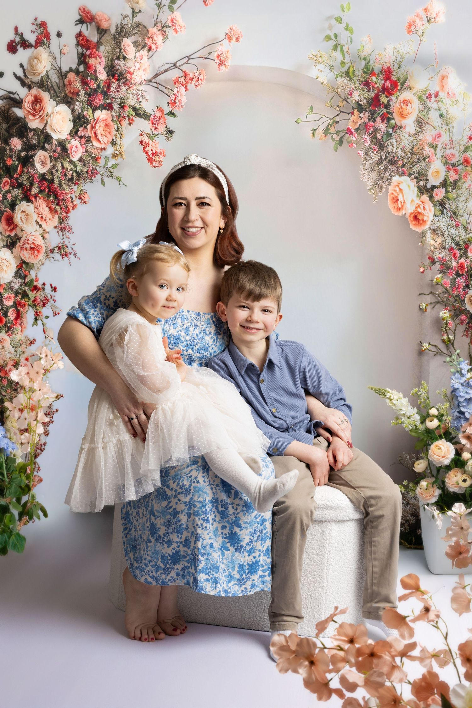 Spring studio portraits with floral decorations featuring pink and peach blooms against a light backdrop.