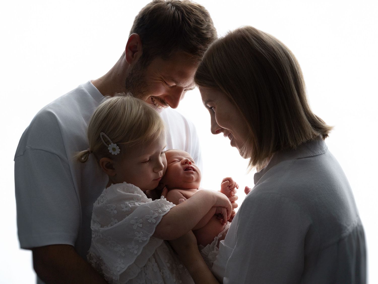 A series of silhouetted family portraits showing tender moments in white clothing.