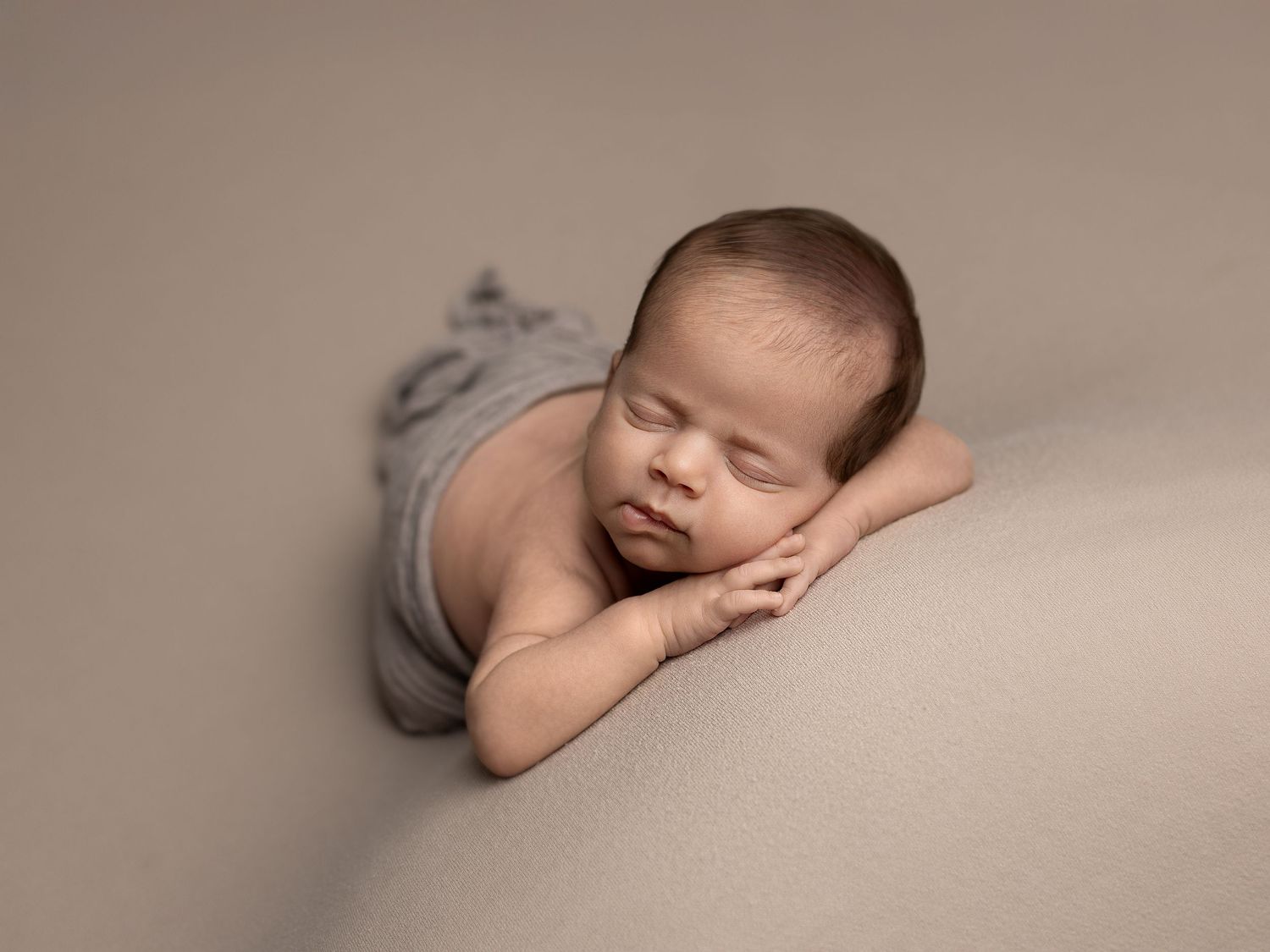 Artistic newborn photography series showing peaceful sleeping poses on neutral backdrop.