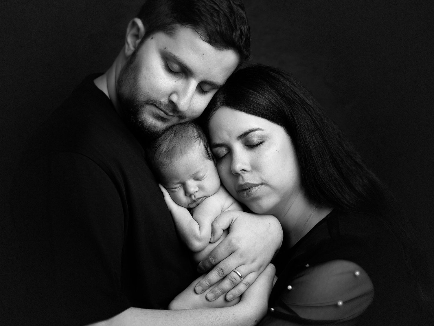 Intimate black and white family portrait in dramatic lighting.