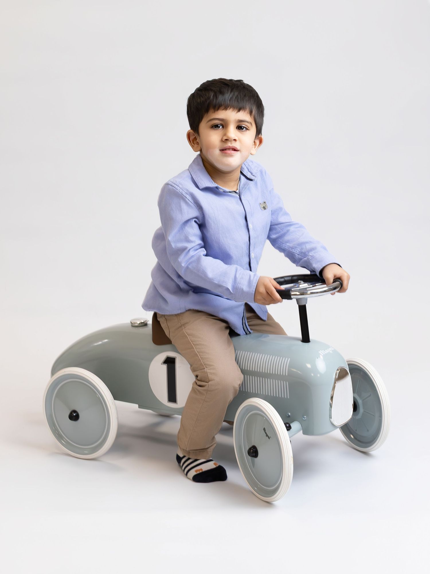 A child rides a sleek modern grey ride-on toy car against a white studio background in three different poses.