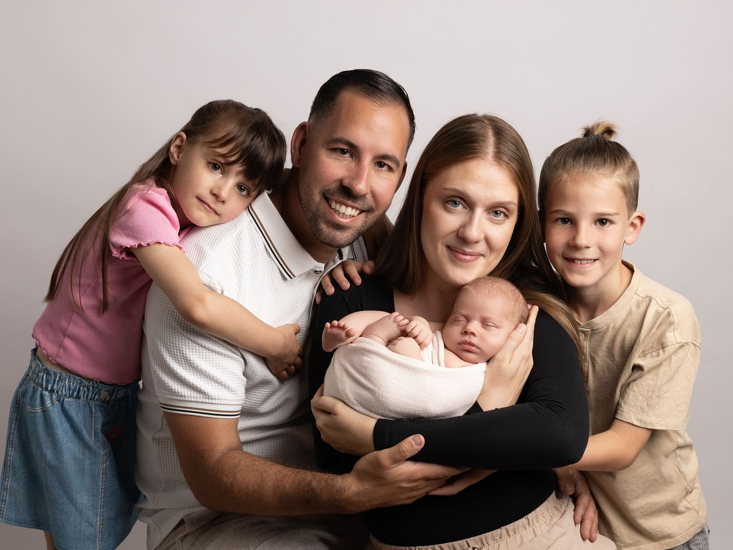 Family portrait series showing tender moments between parents and children on neutral background.
