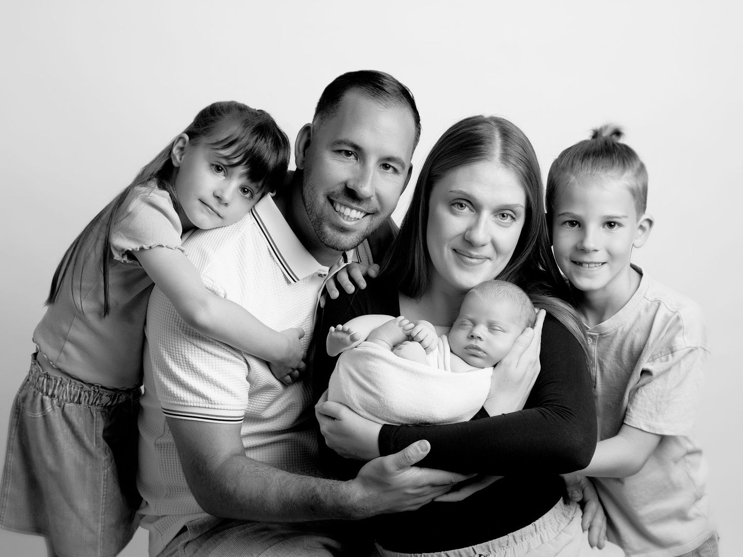 Black and white portrait of a family of five with parents and three children including a newborn baby.