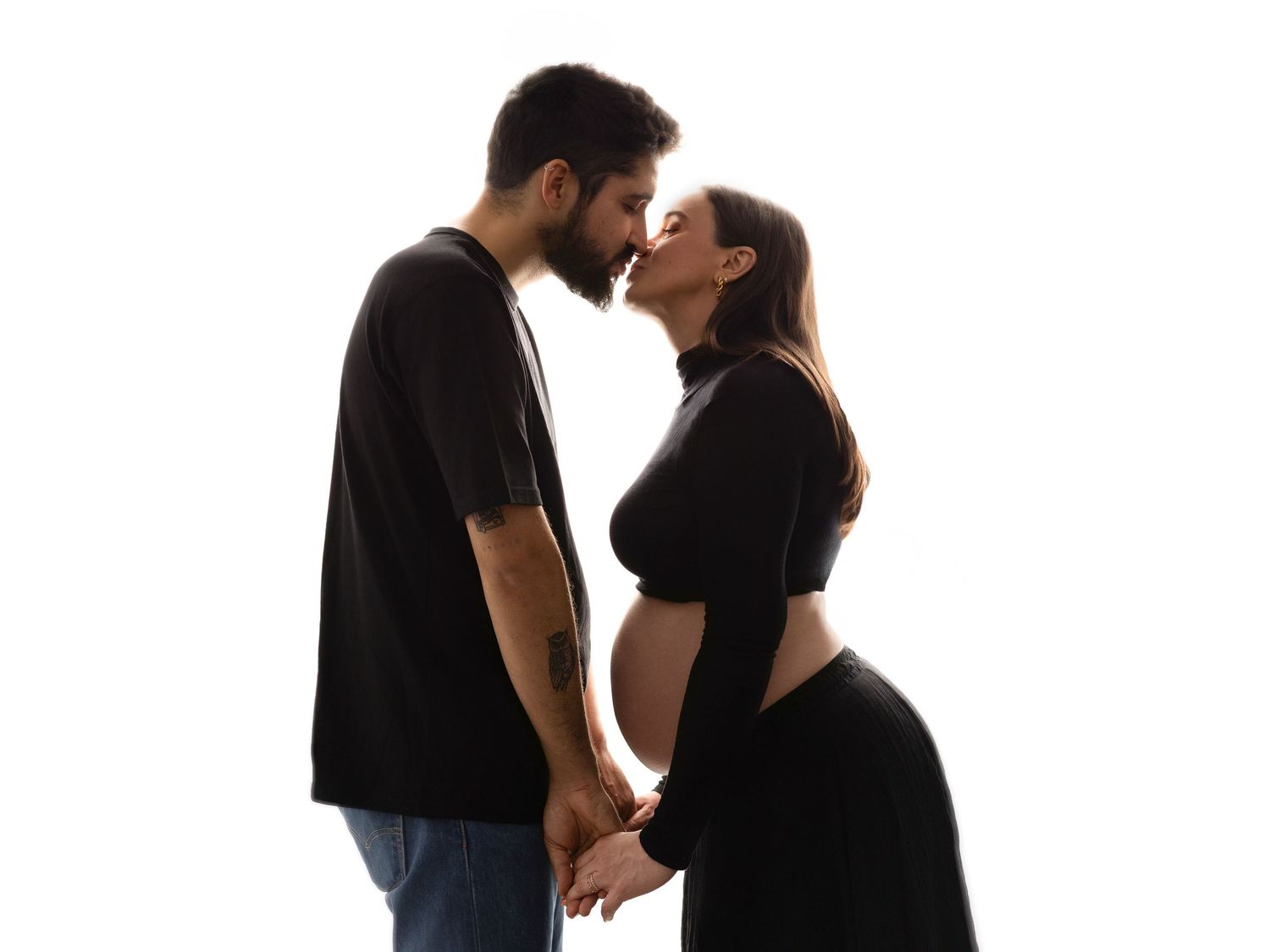 Silhouetted couple sharing tender moment during maternity photoshoot.