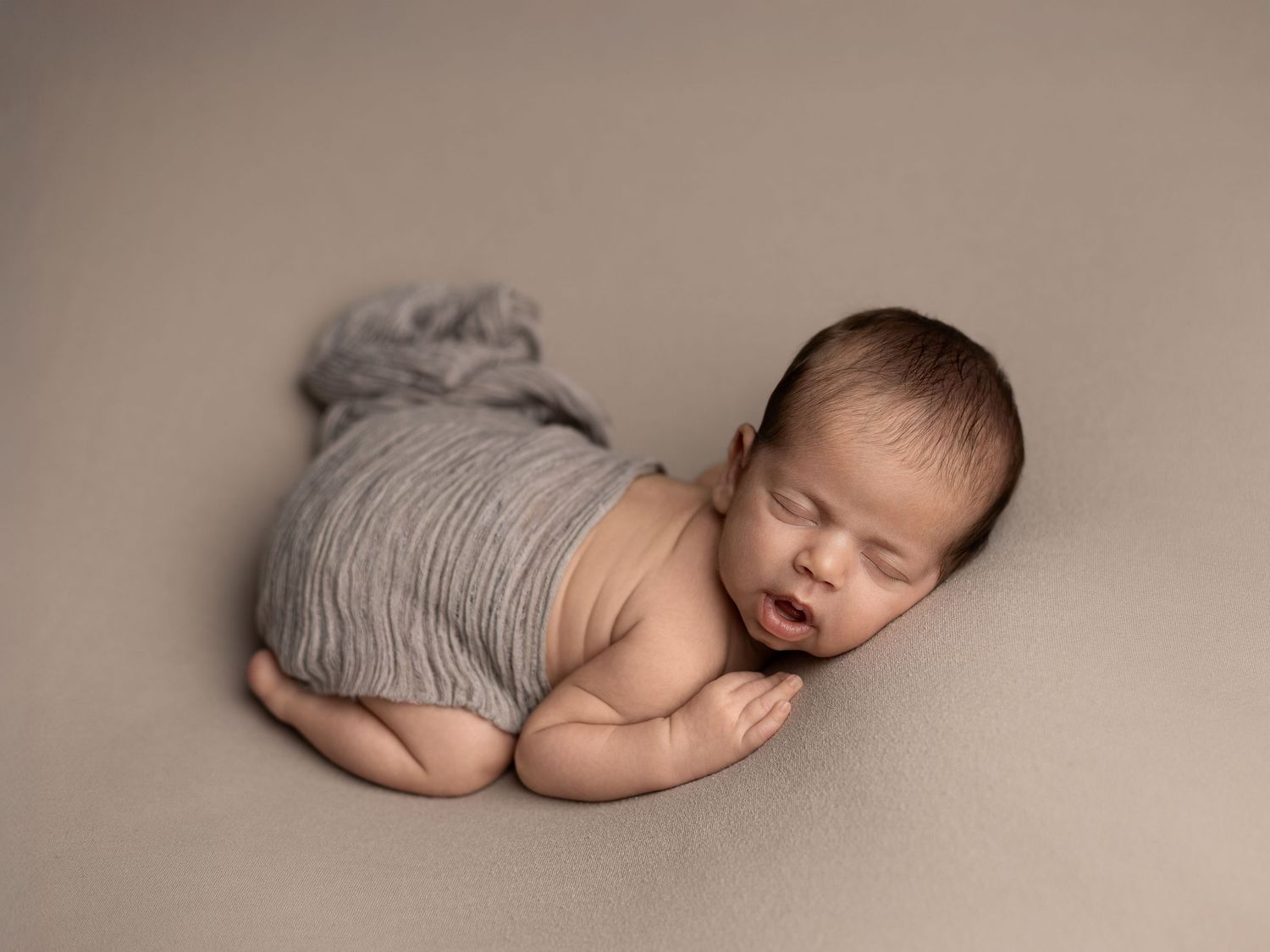 Sleeping newborn baby posed in artistic black and white photography series.