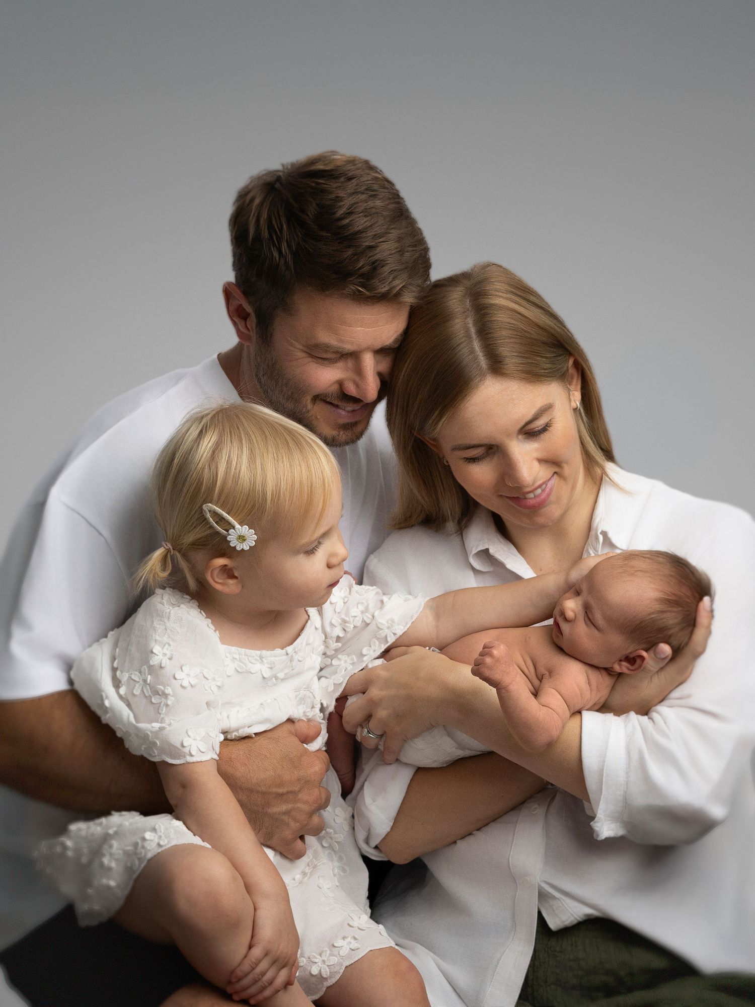 A series of candid family moments photographed in black and white showing affection and connection.