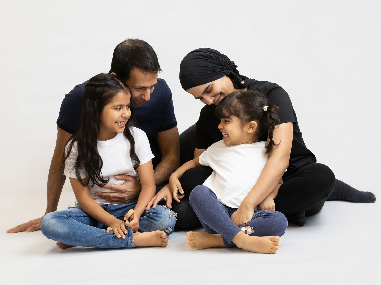 Family members lying on white floor in casual clothing while interacting with each other in progressive poses.