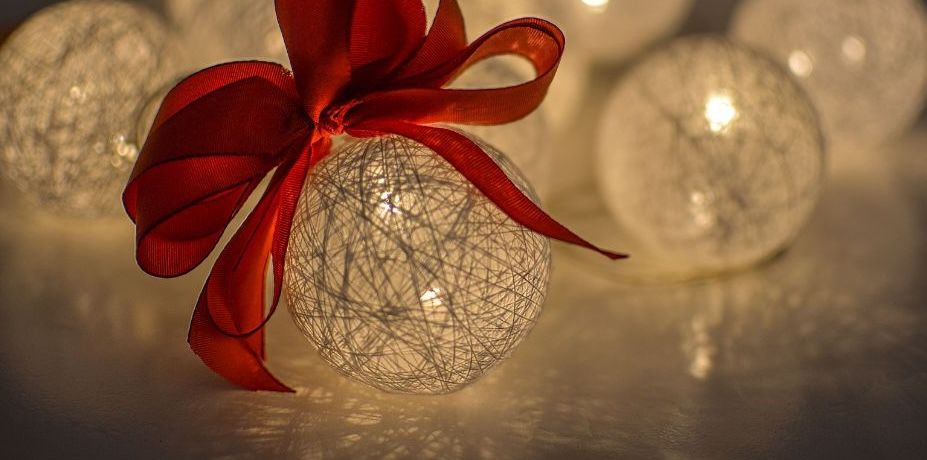 Glowing string ball ornaments with red ribbons create a warm and festive holiday atmosphere.