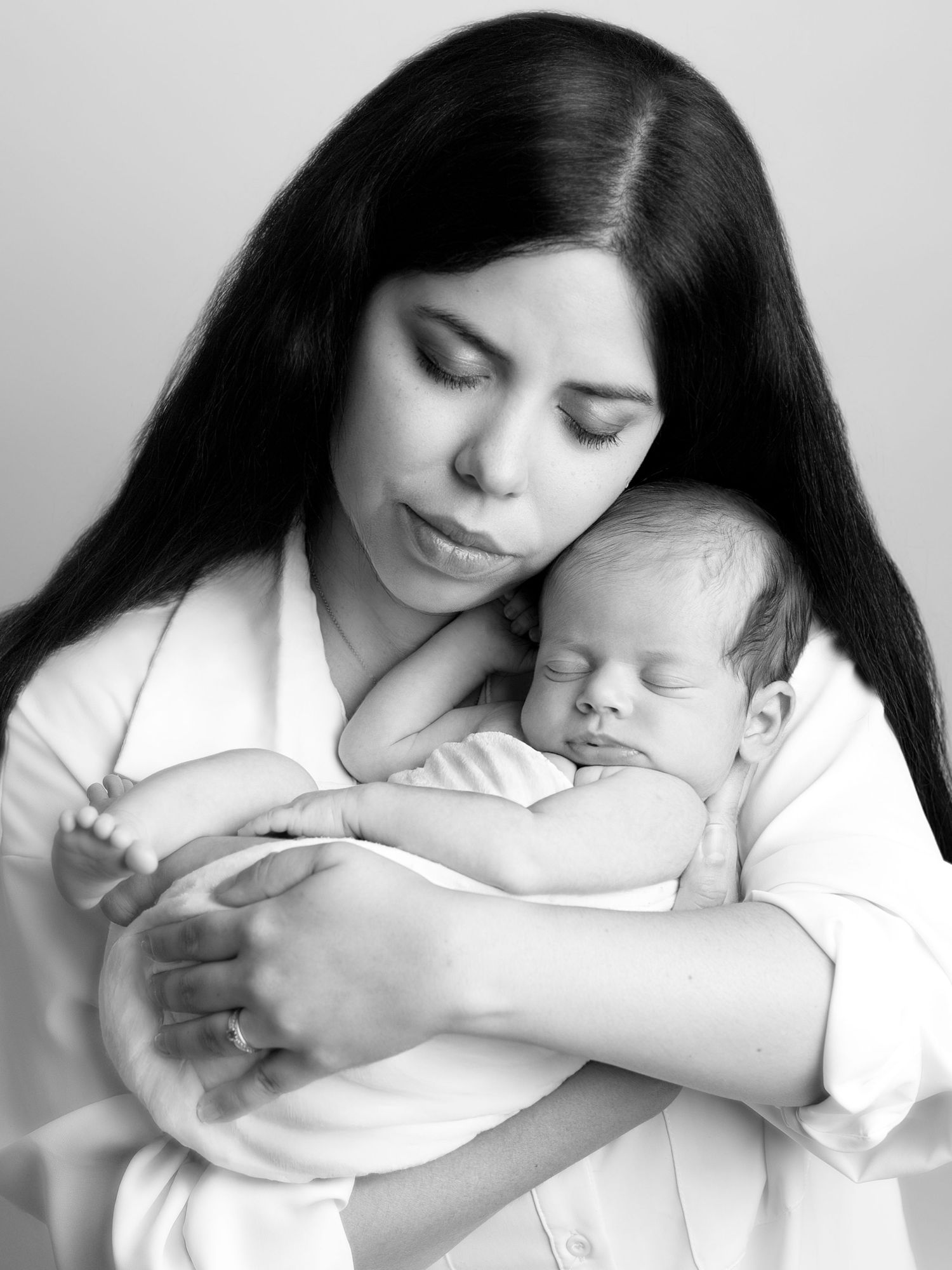 Black and white portrait of tender motherhood moment with sleeping newborn.