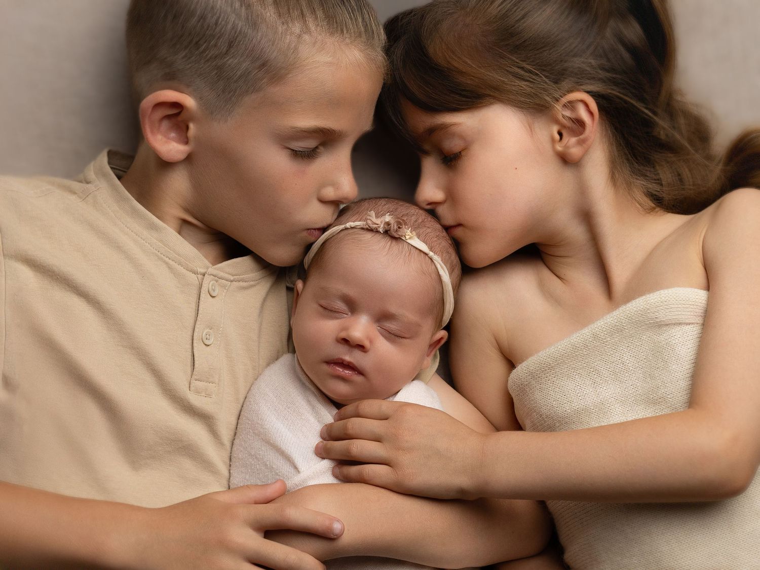 Tender sepia-toned portraits showing gentle embraces with a sleeping infant.