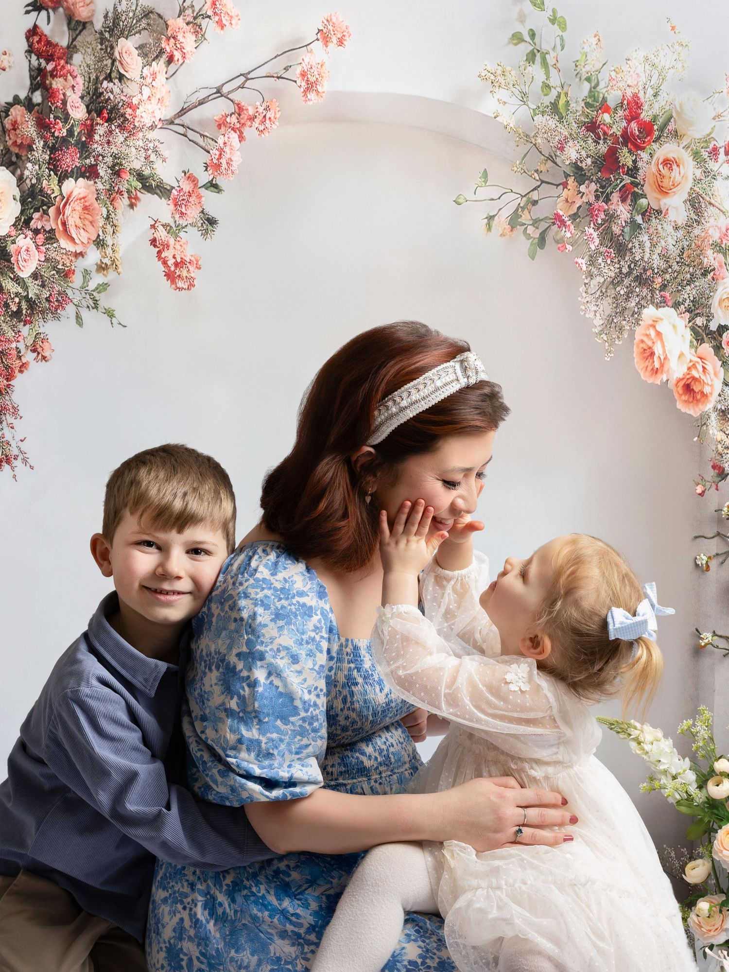 Heartwarming family portrait session with floral backdrop showing tender embraces and joyful interactions.