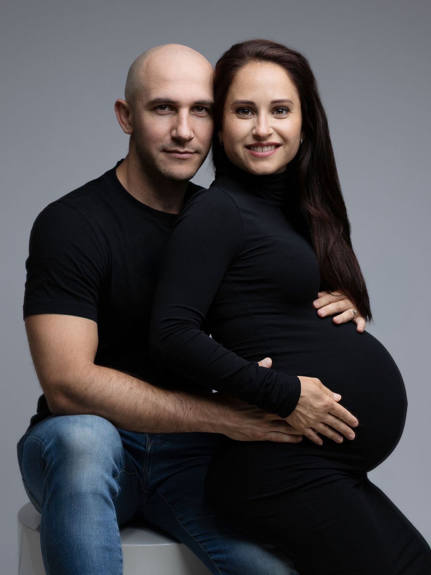 Couple wearing black outfits in studio maternity photoshoot progression.