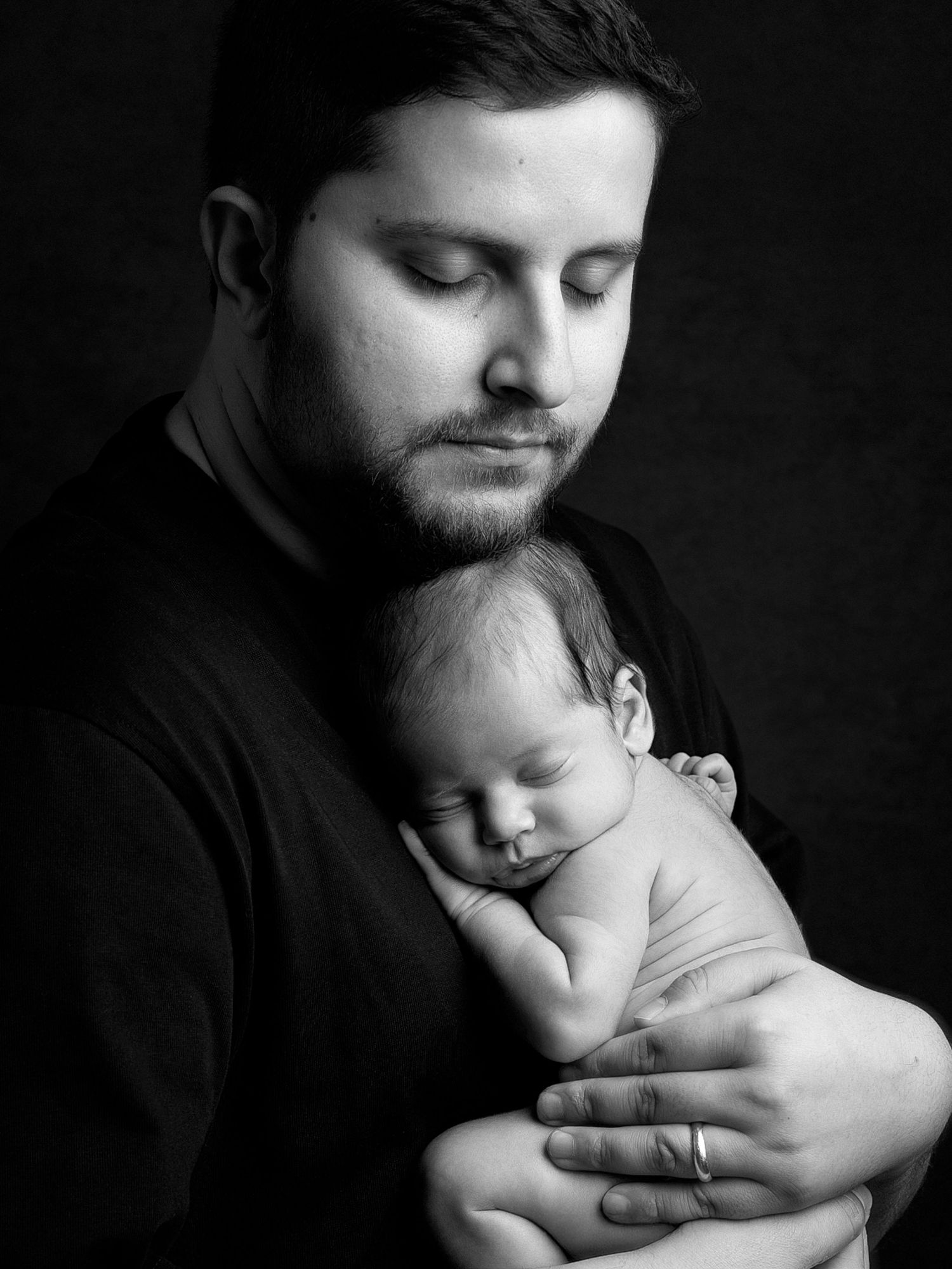 Black and white portrait of paternal bonding with sleeping newborn.