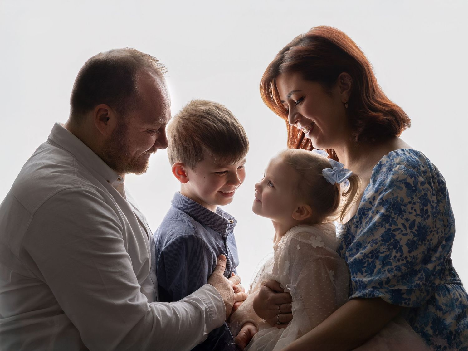 Family members share tender moments in a series of black and white profile portraits against a light background.