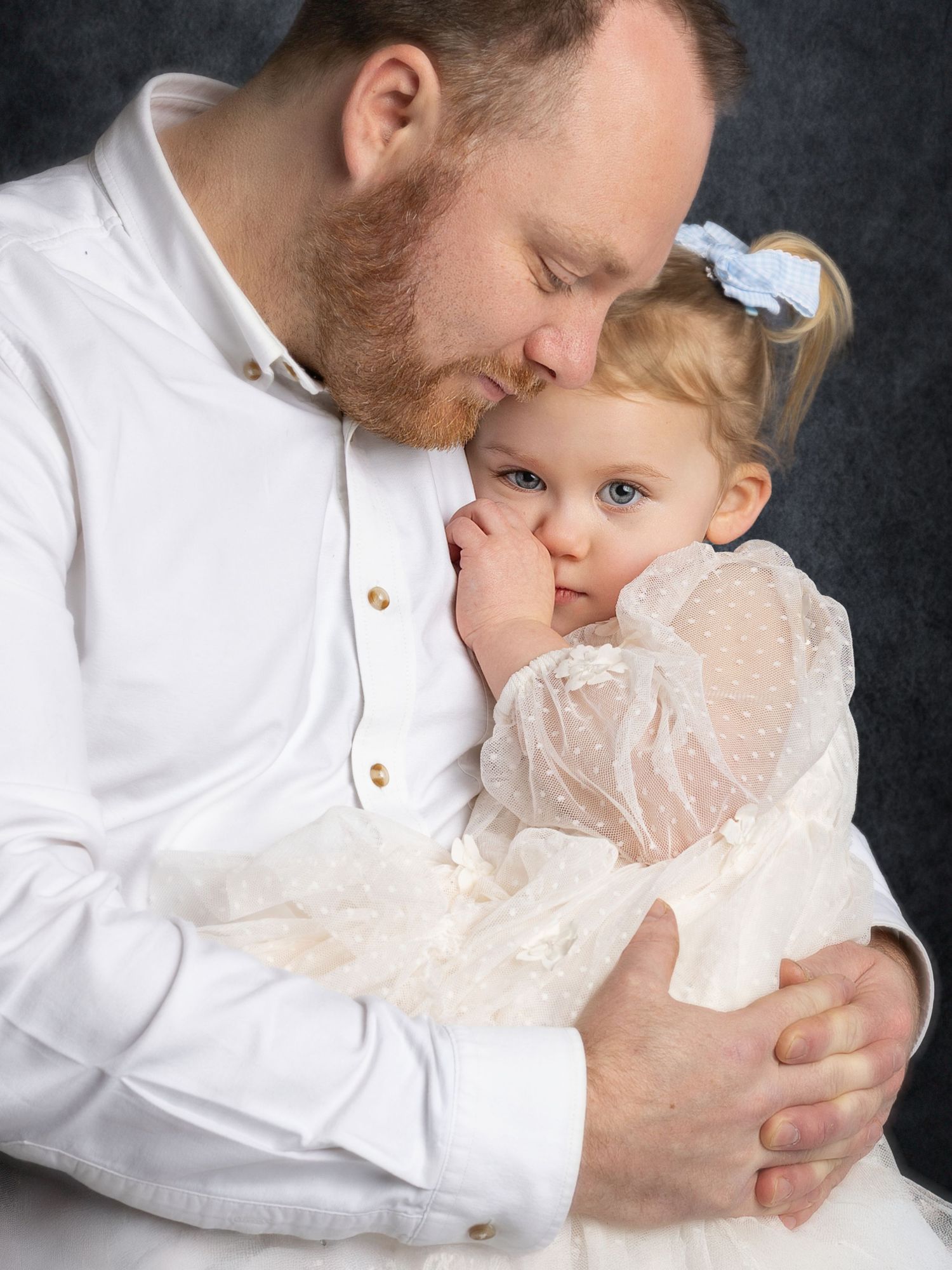 A tender moment captured in a studio portrait series showing gentle embraces against a dark background.