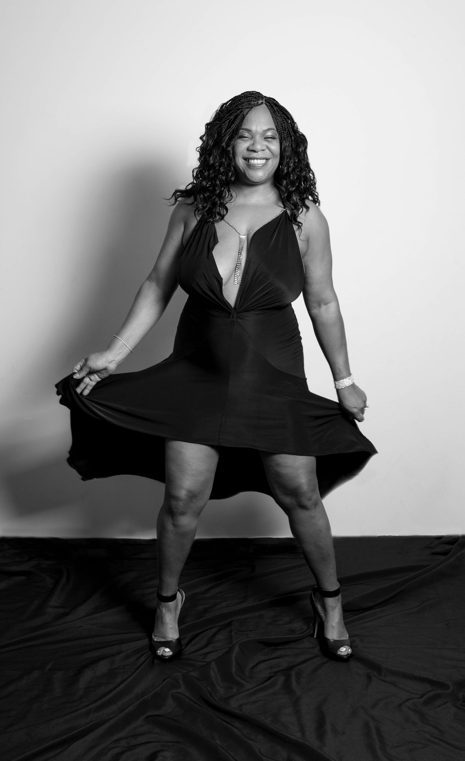 Woman in black dress poses confidently in a black and white studio portrait photo.