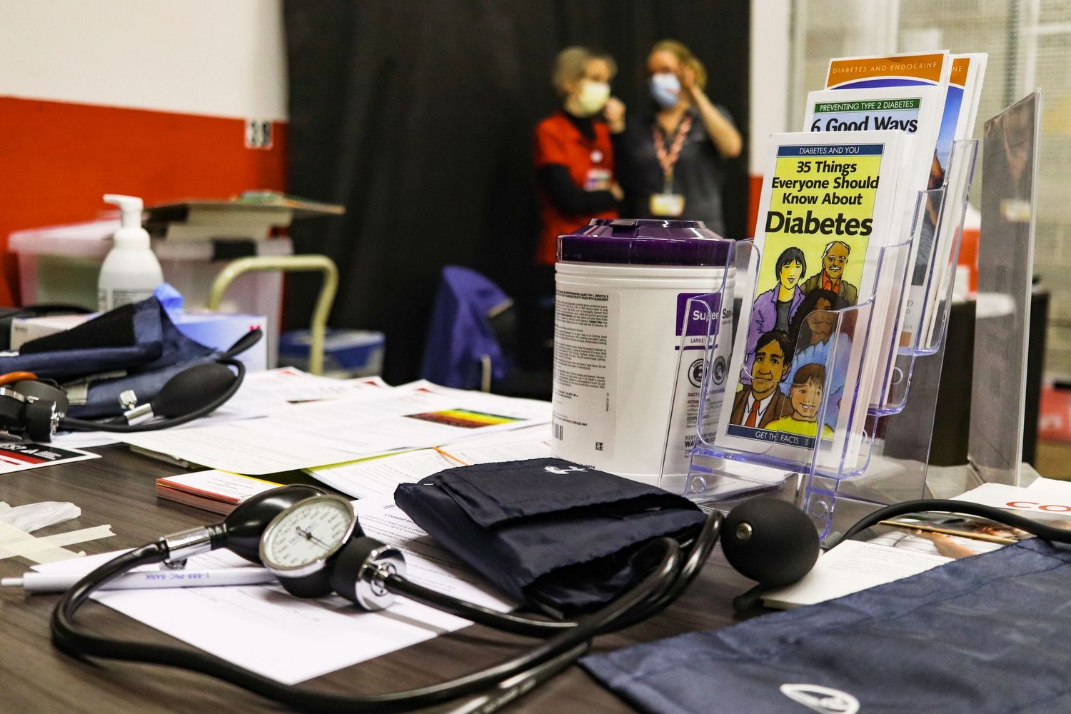 A medical table displays a stethoscope, blood pressure cuff, and diabetes health brochures at a clinic.