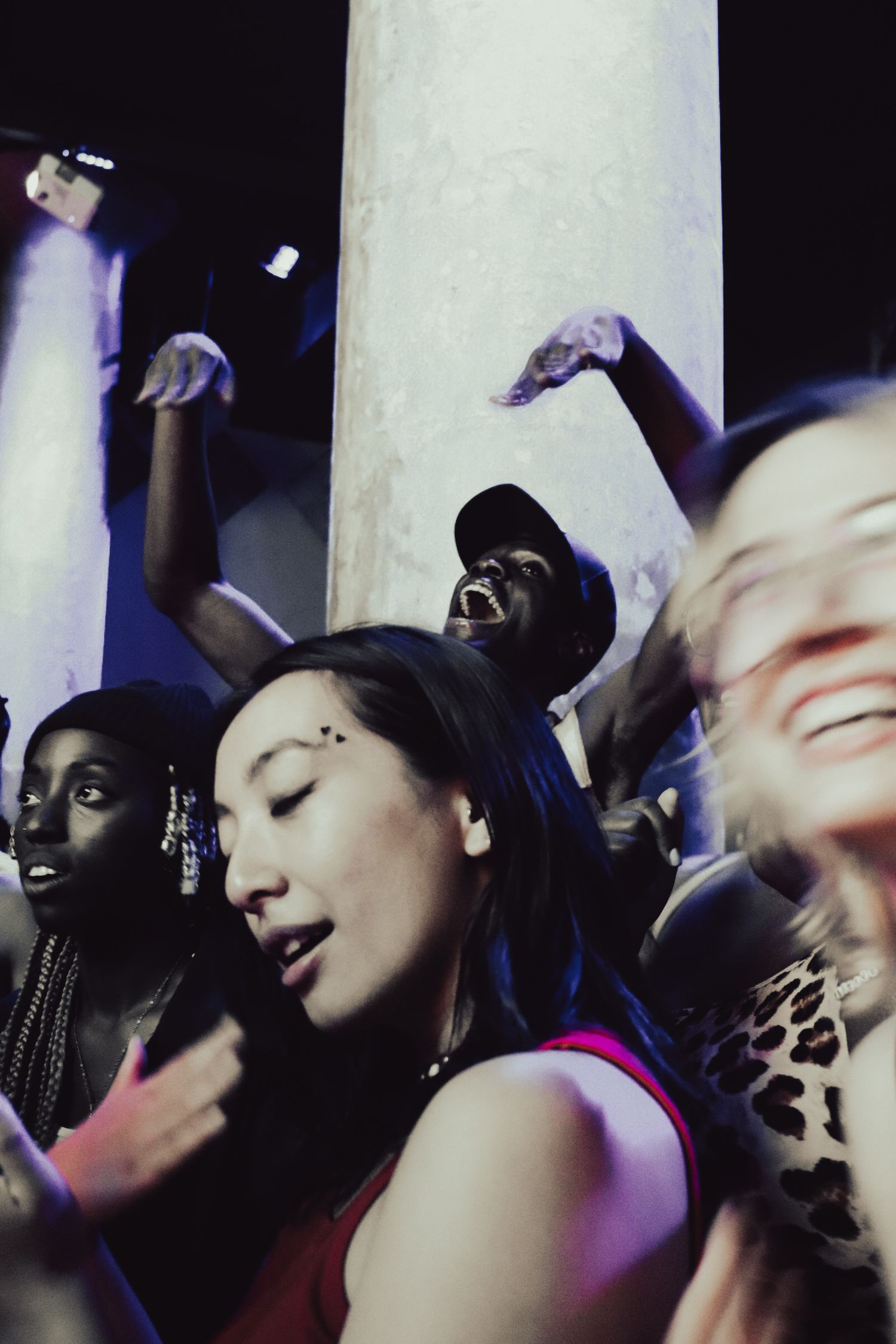 Diverse group of concert-goers dancing and celebrating at a lively nightclub event.