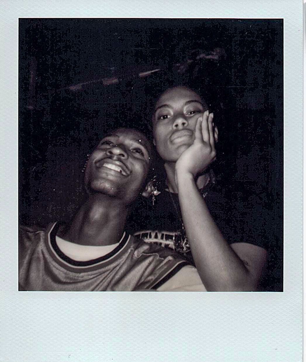 Vintage Polaroid photo of two young Black women smiling in low light.