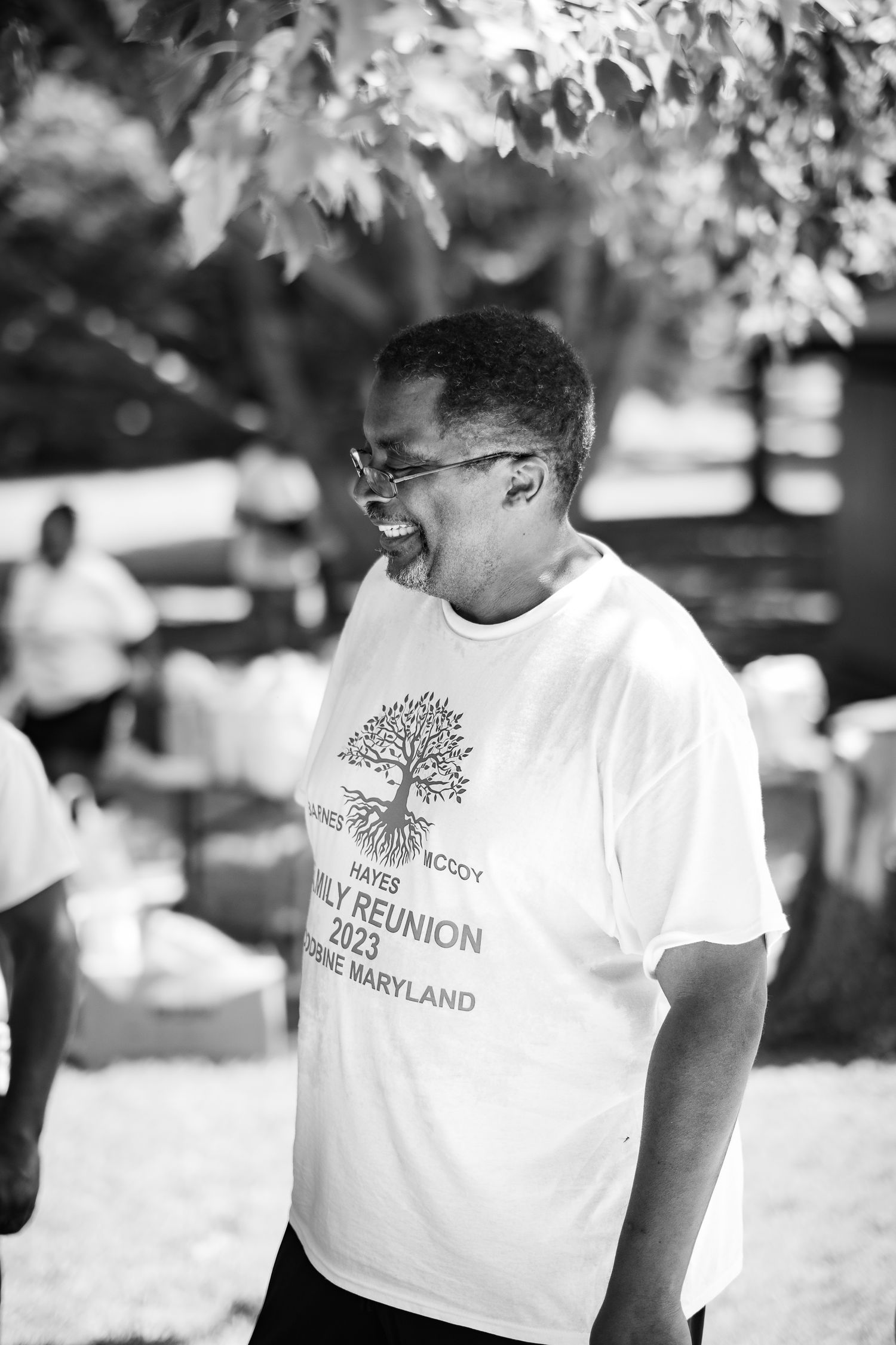 A smiling person wearing a 2023 Family Reunion Maryland t-shirt at an outdoor gathering.