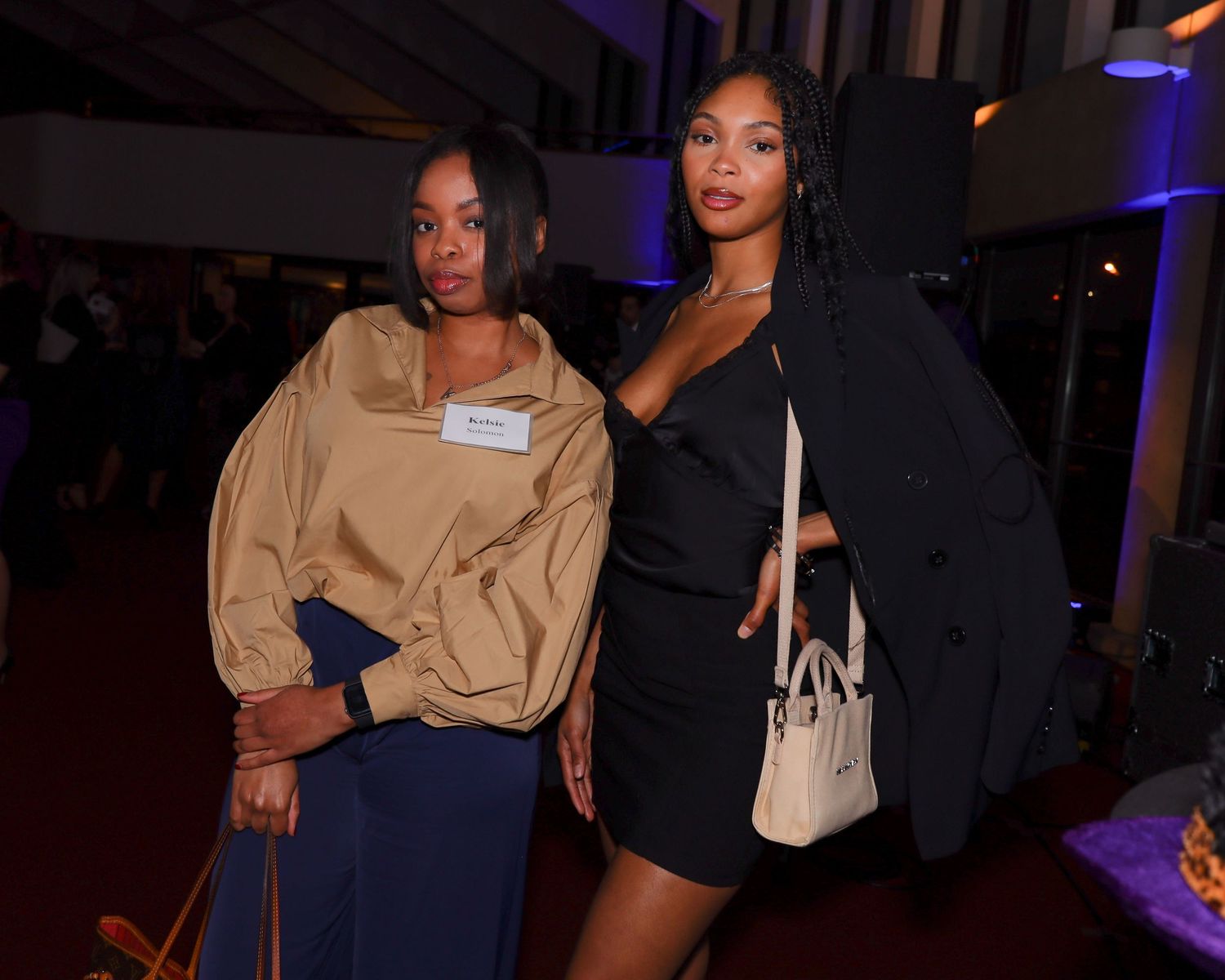 Two stylish women posing together at a formal evening networking event.