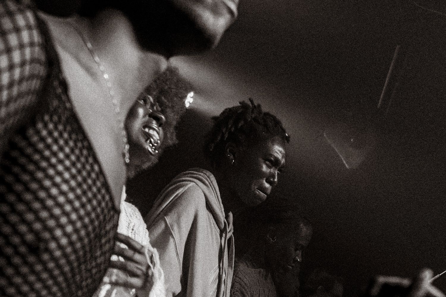 Black and white photo of people dancing closely together at a dimly lit music venue.