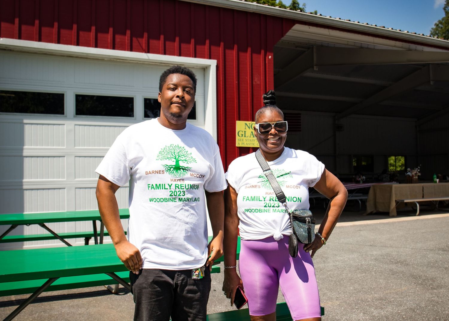 Two people wearing 2023 Family Reunion t-shirts pose together outside a red barn building.