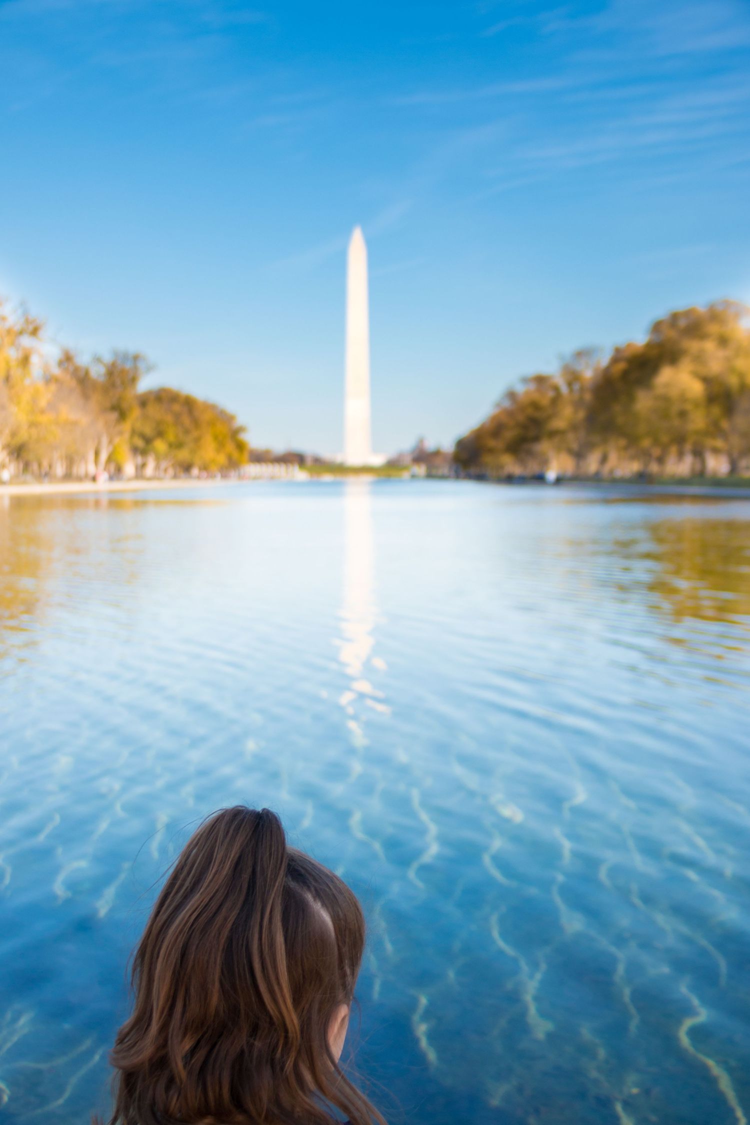 A woman views the Washington Monument reflected in the calm waters of the Lincoln Memorial Reflecting Pool.