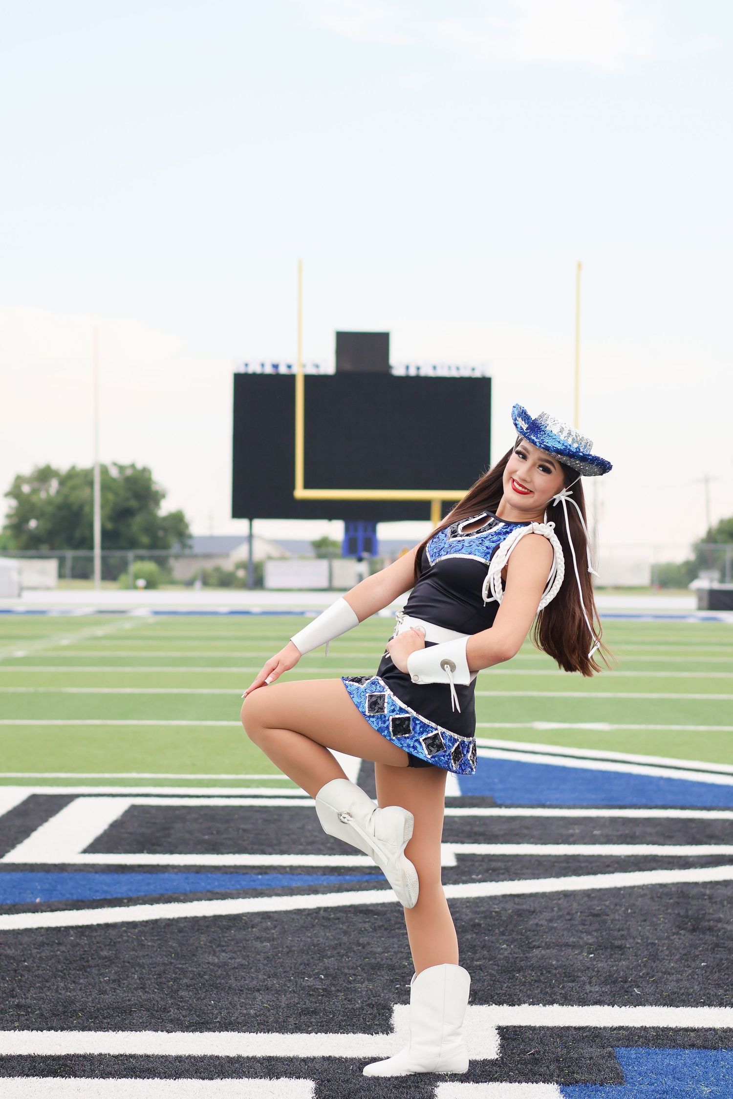A cheerleader performs a high kick sequence on a football field with athletic precision and energy.