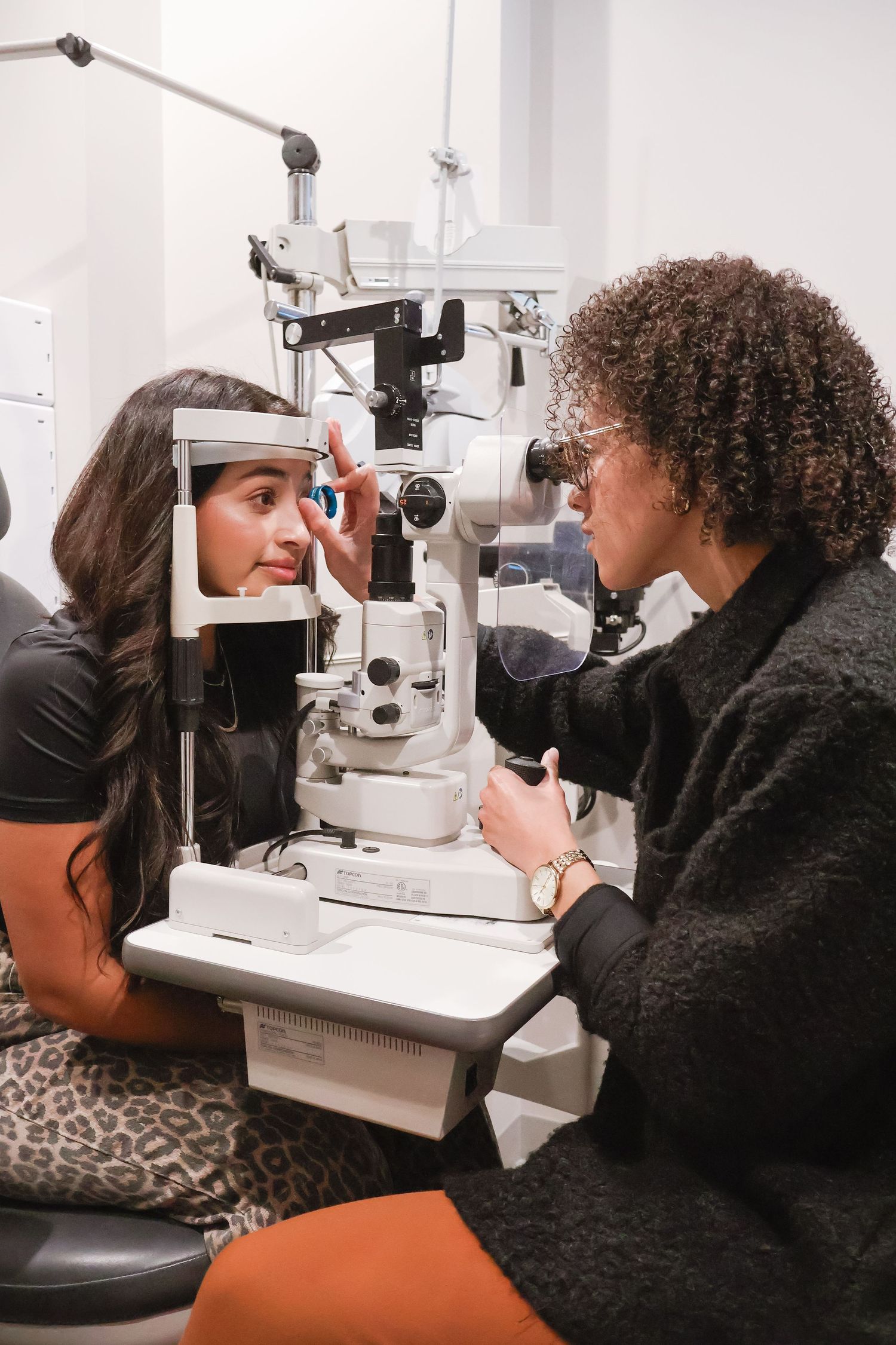 Patient receiving eye examination at optometry clinic with specialized equipment.
