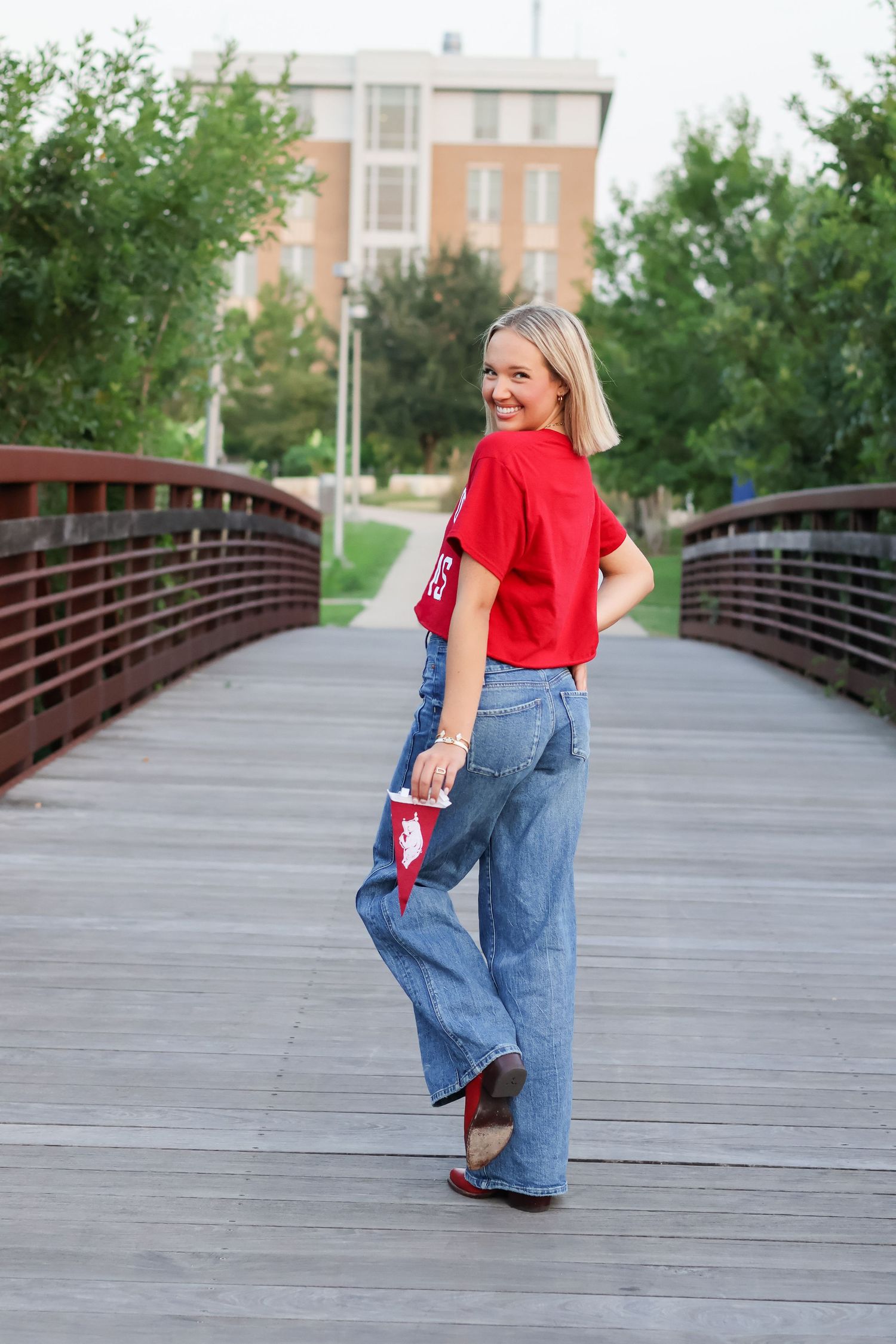 A sequence of photos showing a person in red shirt and jeans walking playfully across a wooden bridge walkway.