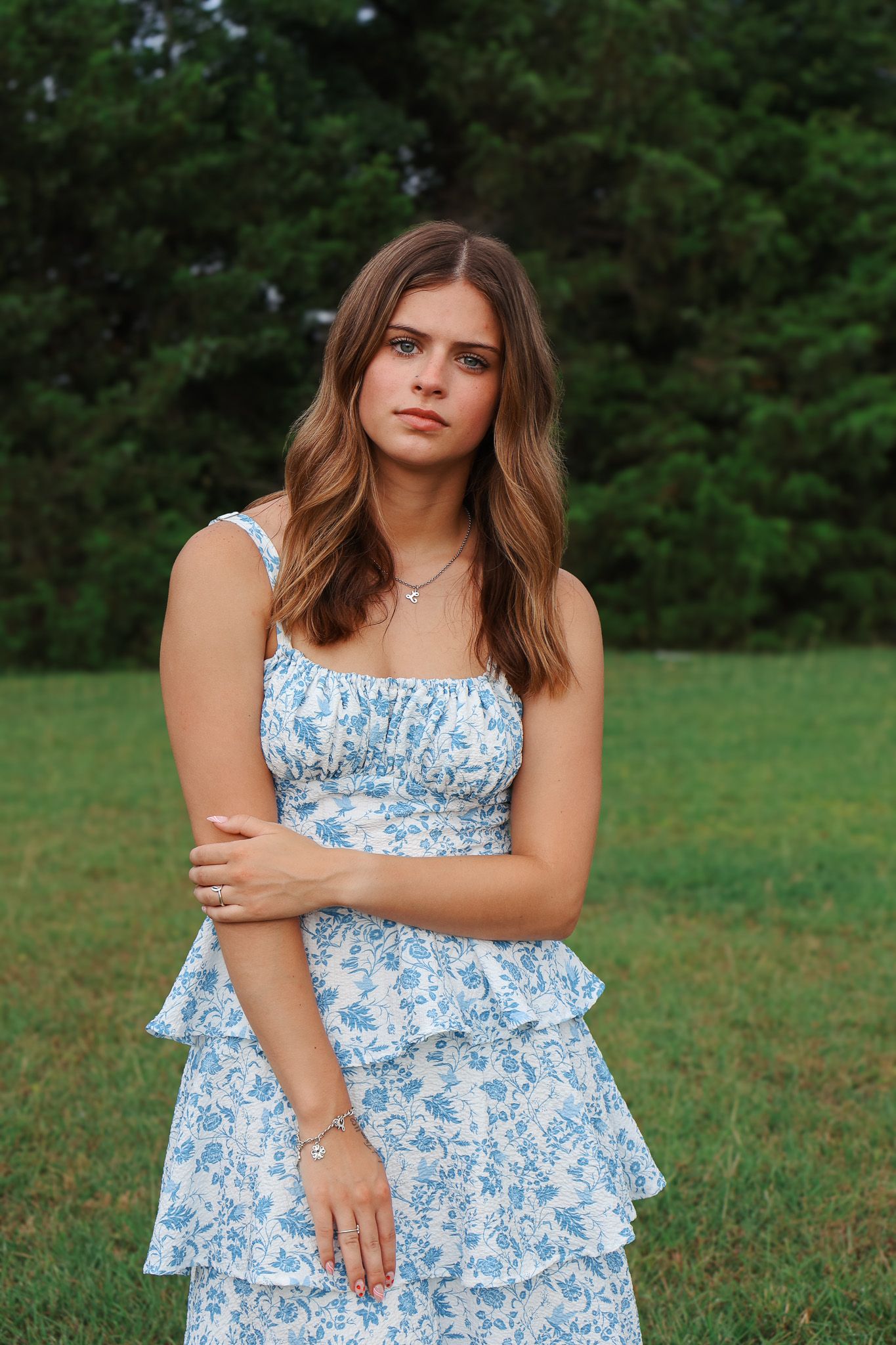 Summer fashion poses in a blue and white floral dress against a grassy outdoor backdrop.