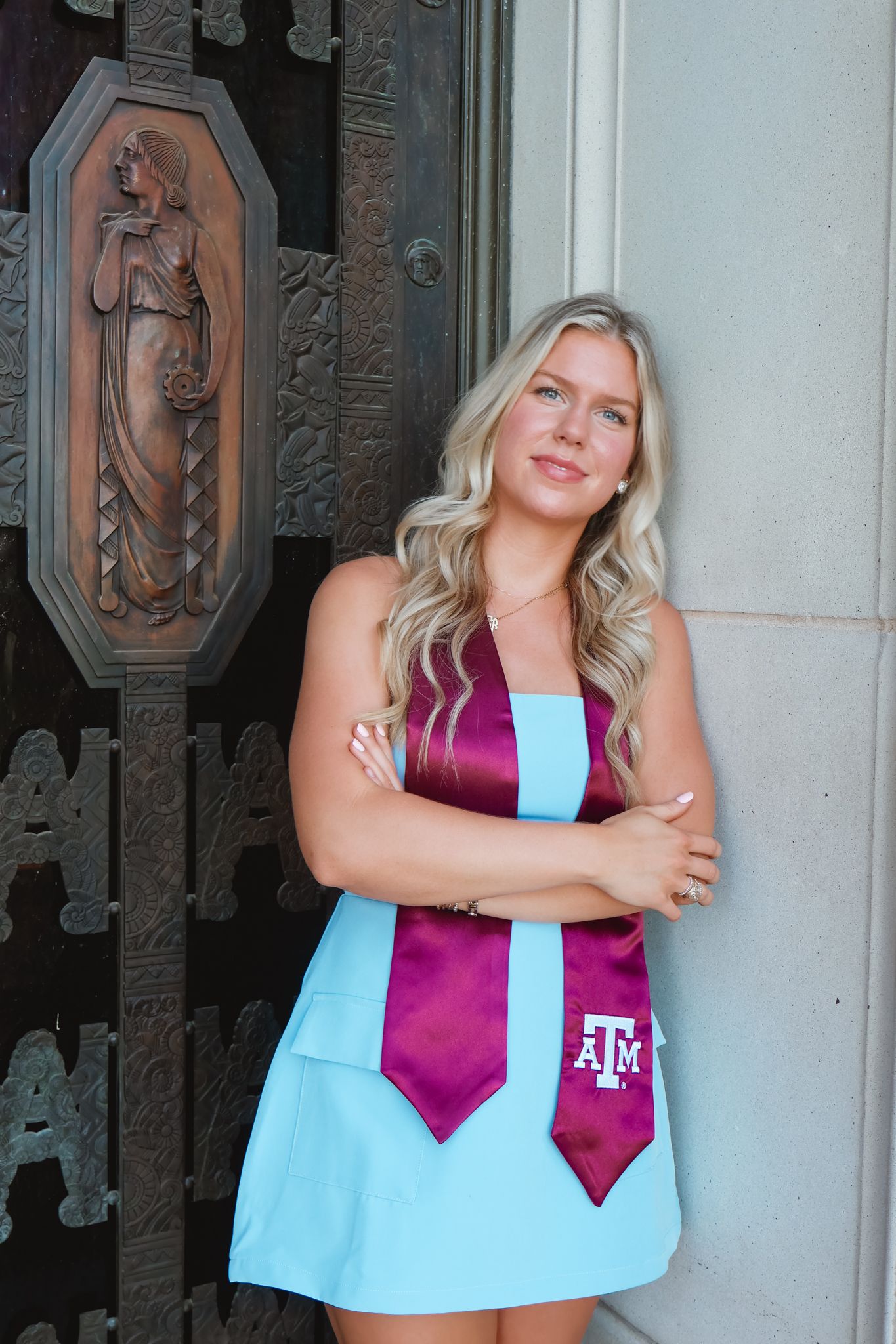 Texas A&M student poses in a stylish blue and maroon game day dress against an ornate door.