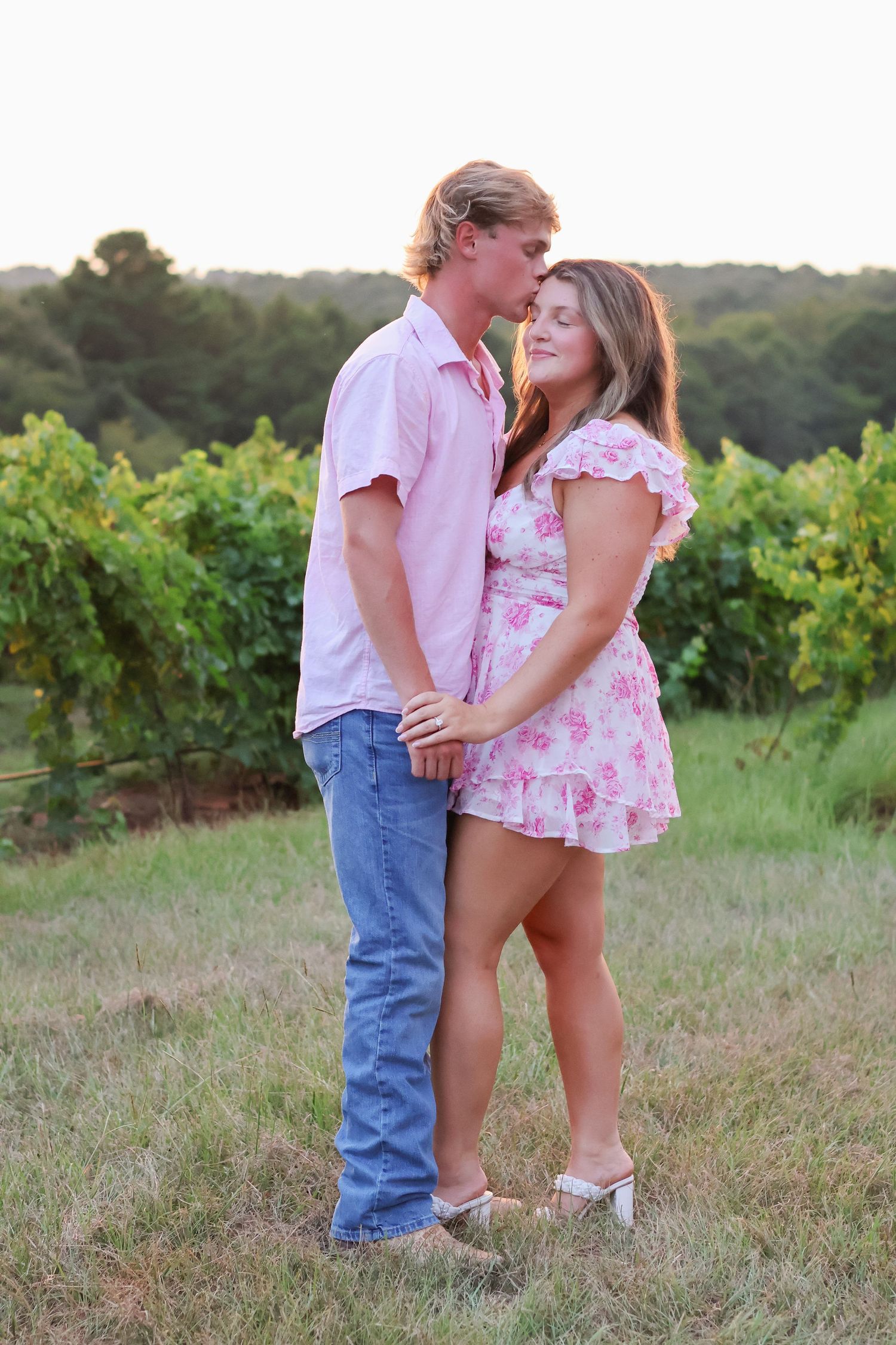 A romantic couple shares tender moments in a vineyard at sunset.
