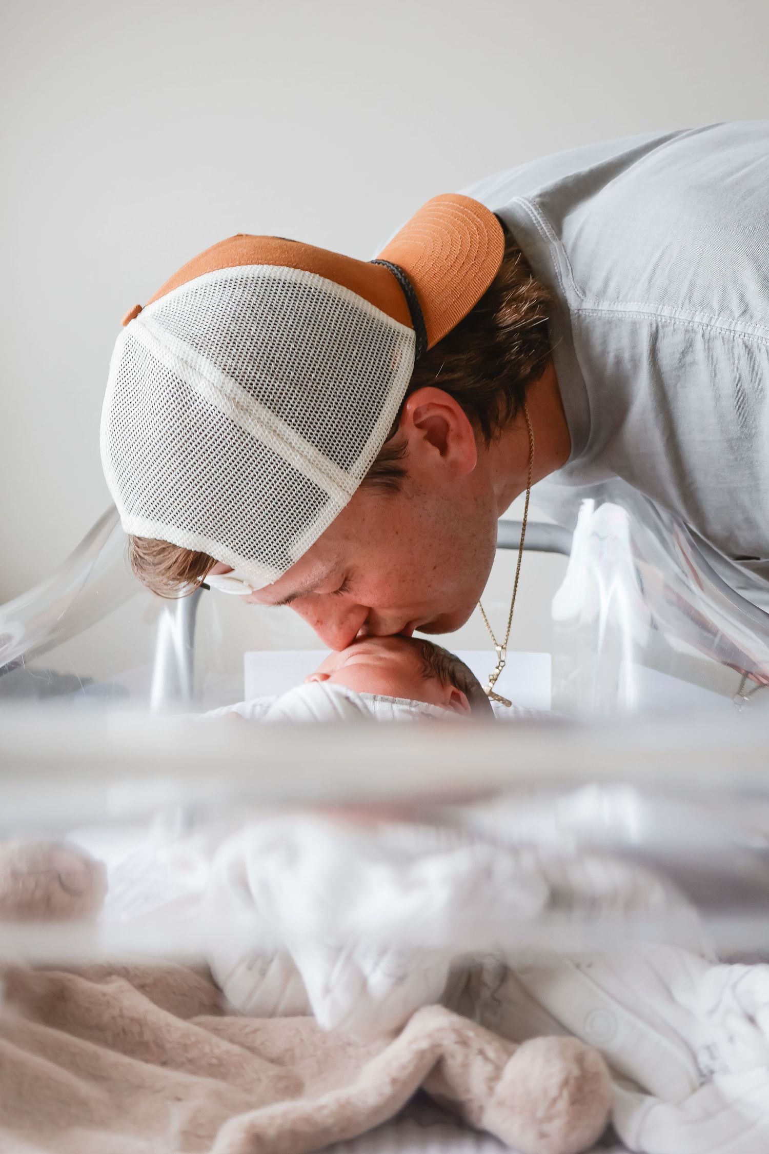 Person wearing white baseball cap lying down on white surface in artistic photo series.