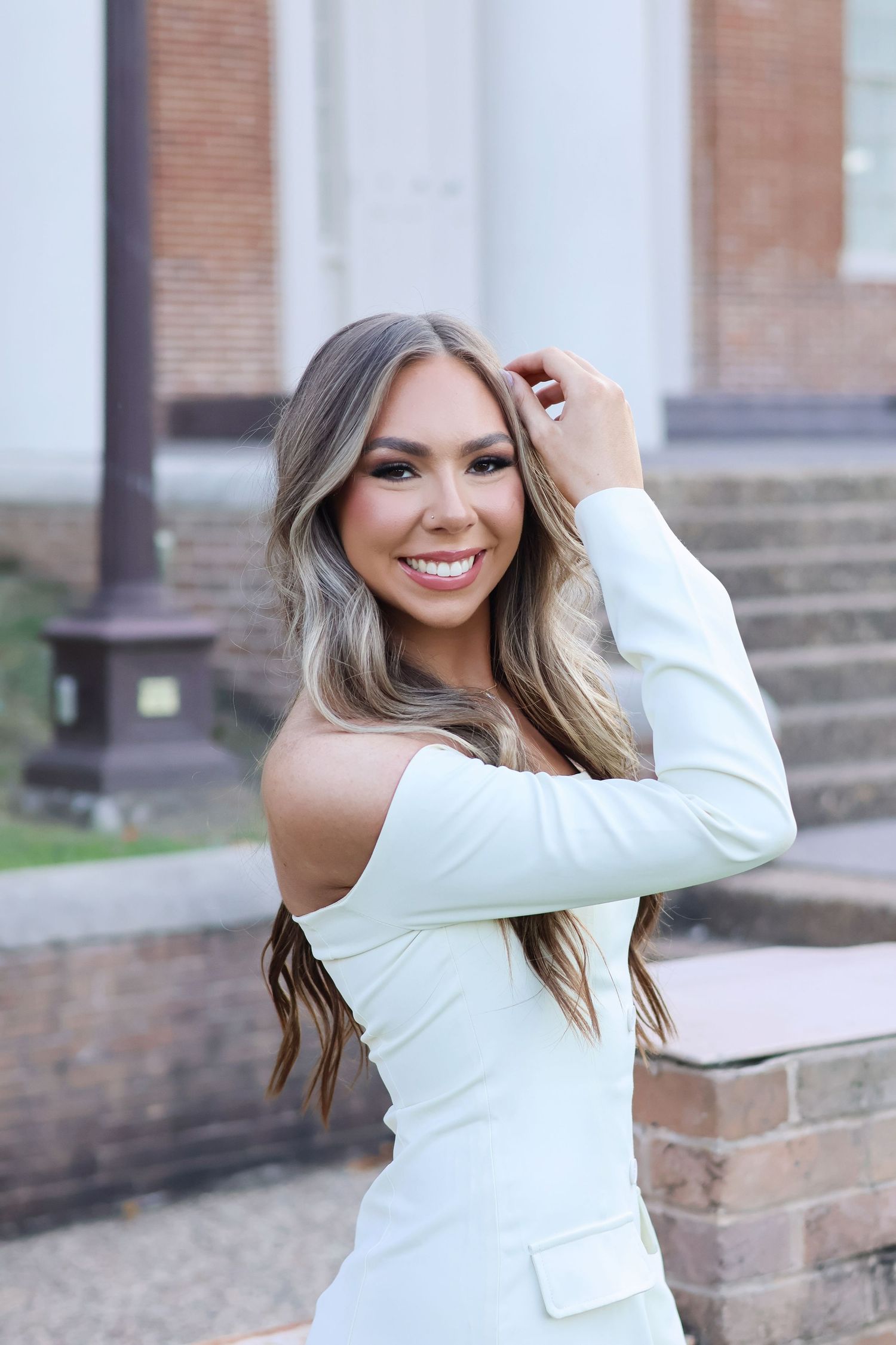 A woman in a white long-sleeve top poses against a brick wall in a series of outdoor portrait shots.