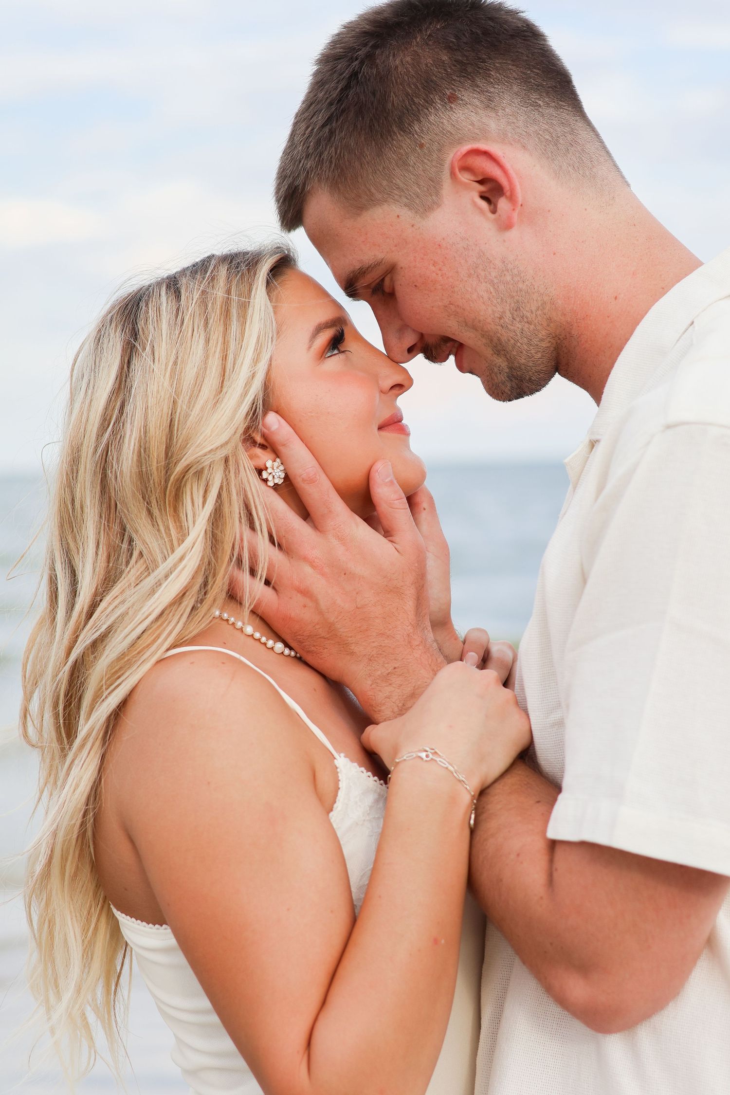 A romantic beach photoshoot sequence shows a couple in white outfits sharing intimate moments by the ocean.