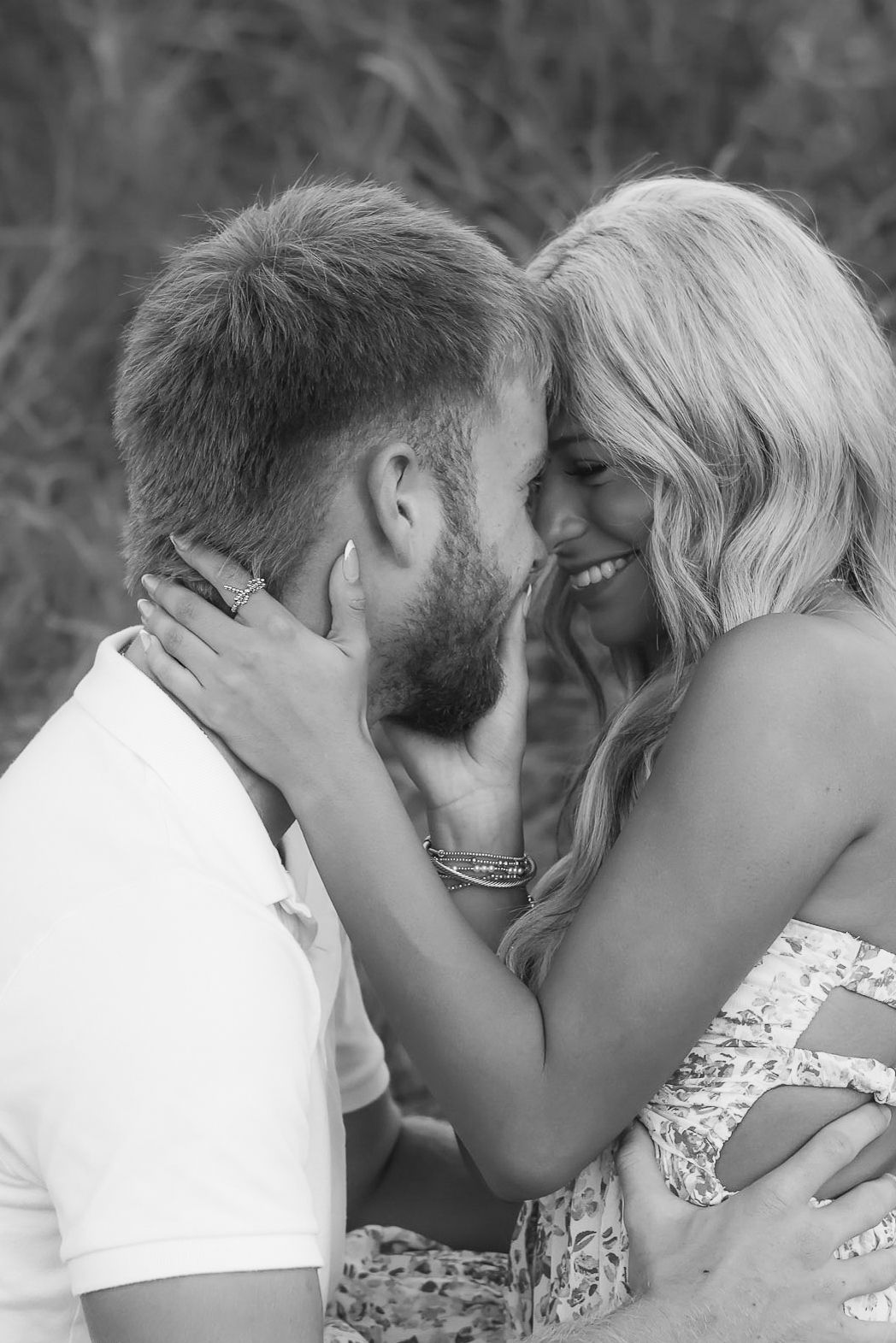 A romantic black and white portrait of a couple sharing an intimate moment outdoors.