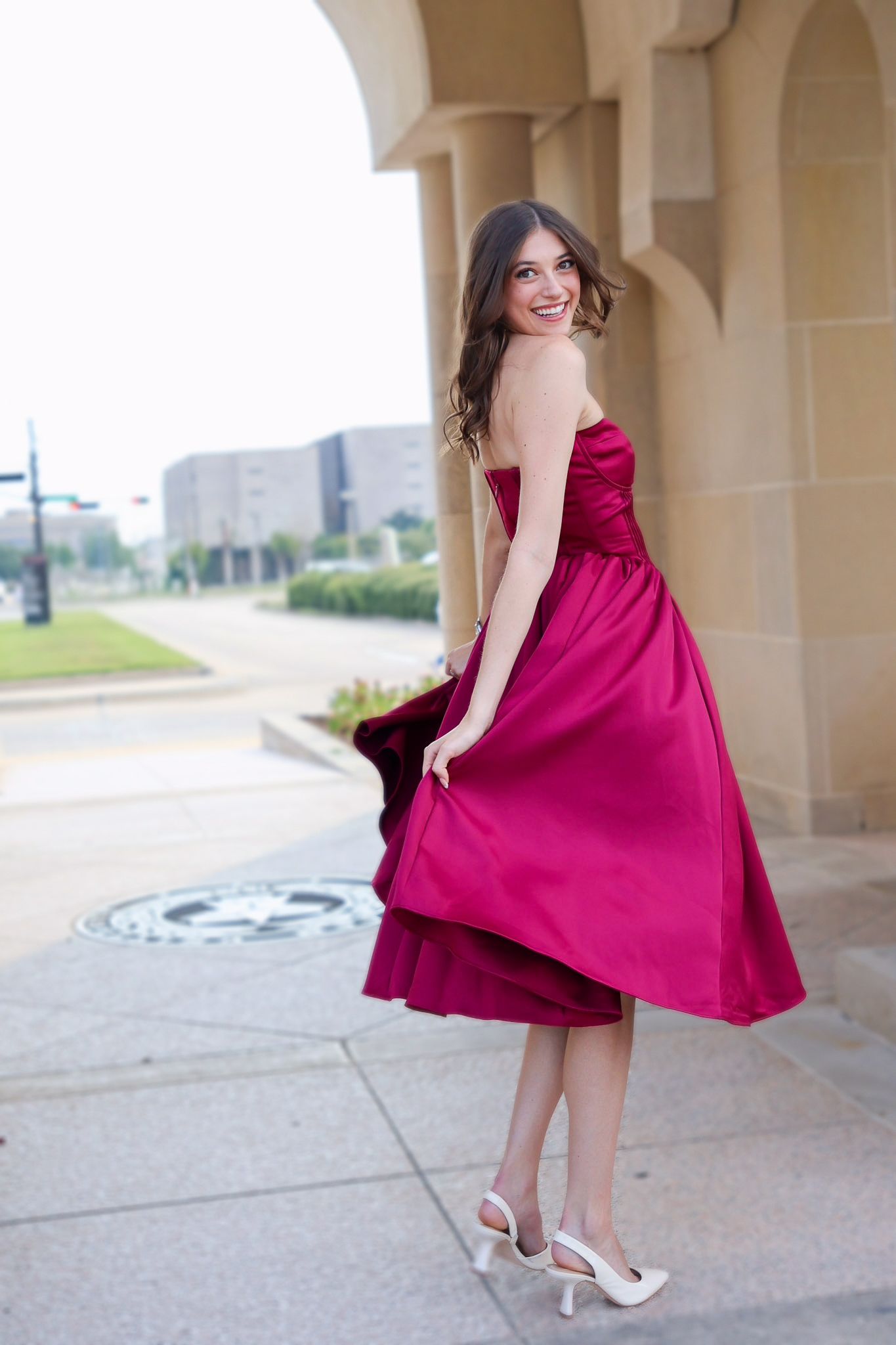 A person in a flowing burgundy dress twirls playfully under stone archways in a series of connected photos.