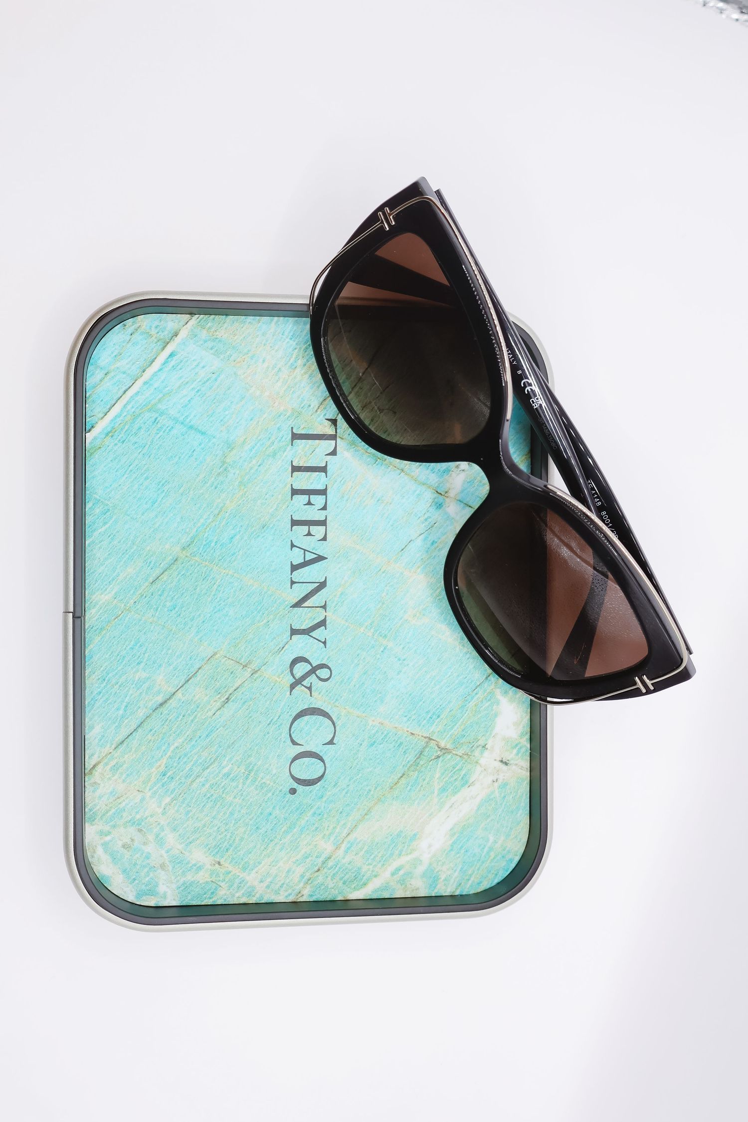 Sunglasses displayed on turquoise marble-patterned surface in product photography.