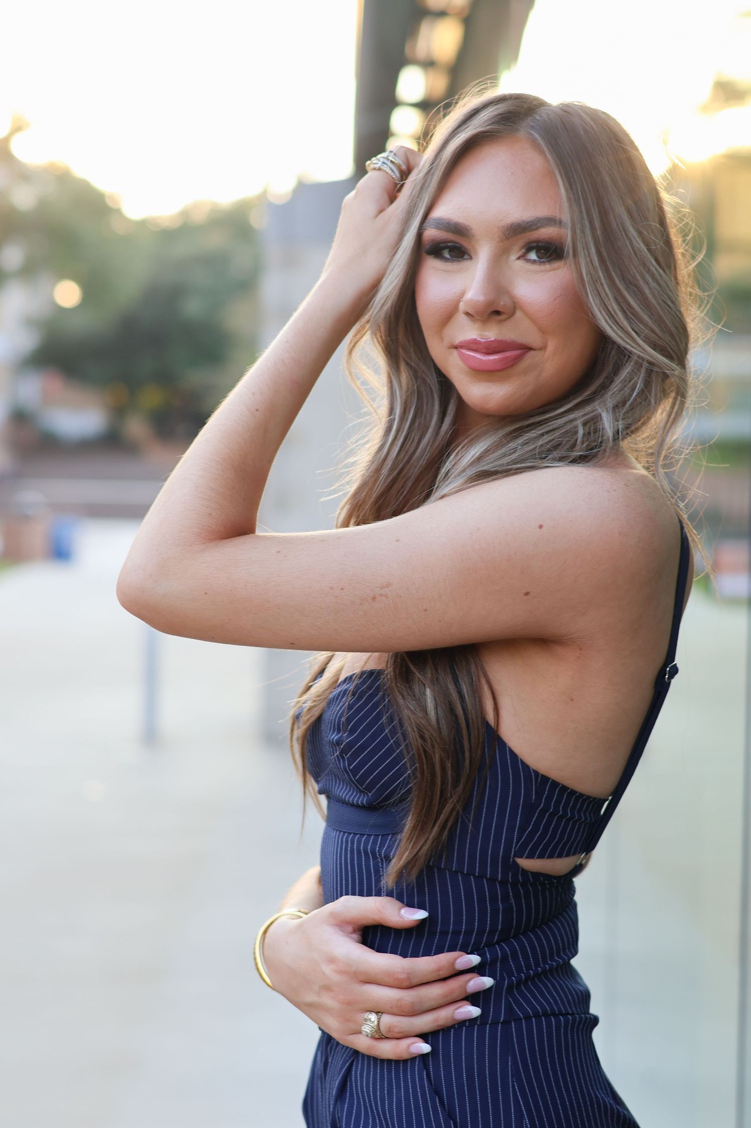 Woman in navy blue striped dress poses outdoors during golden hour in a series of candid shots.
