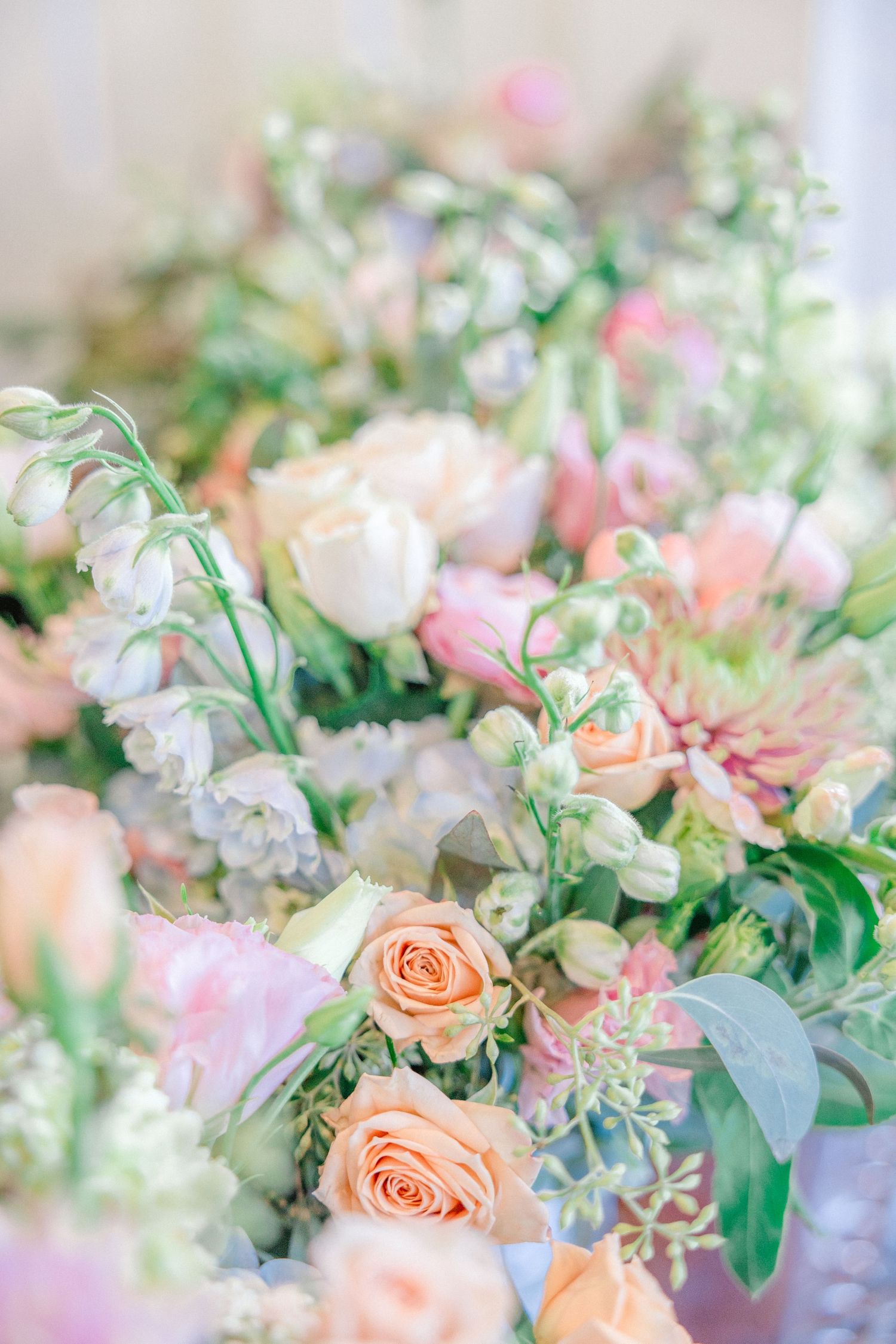 Romantic floral arrangement with peach roses and greenery in soft natural light.