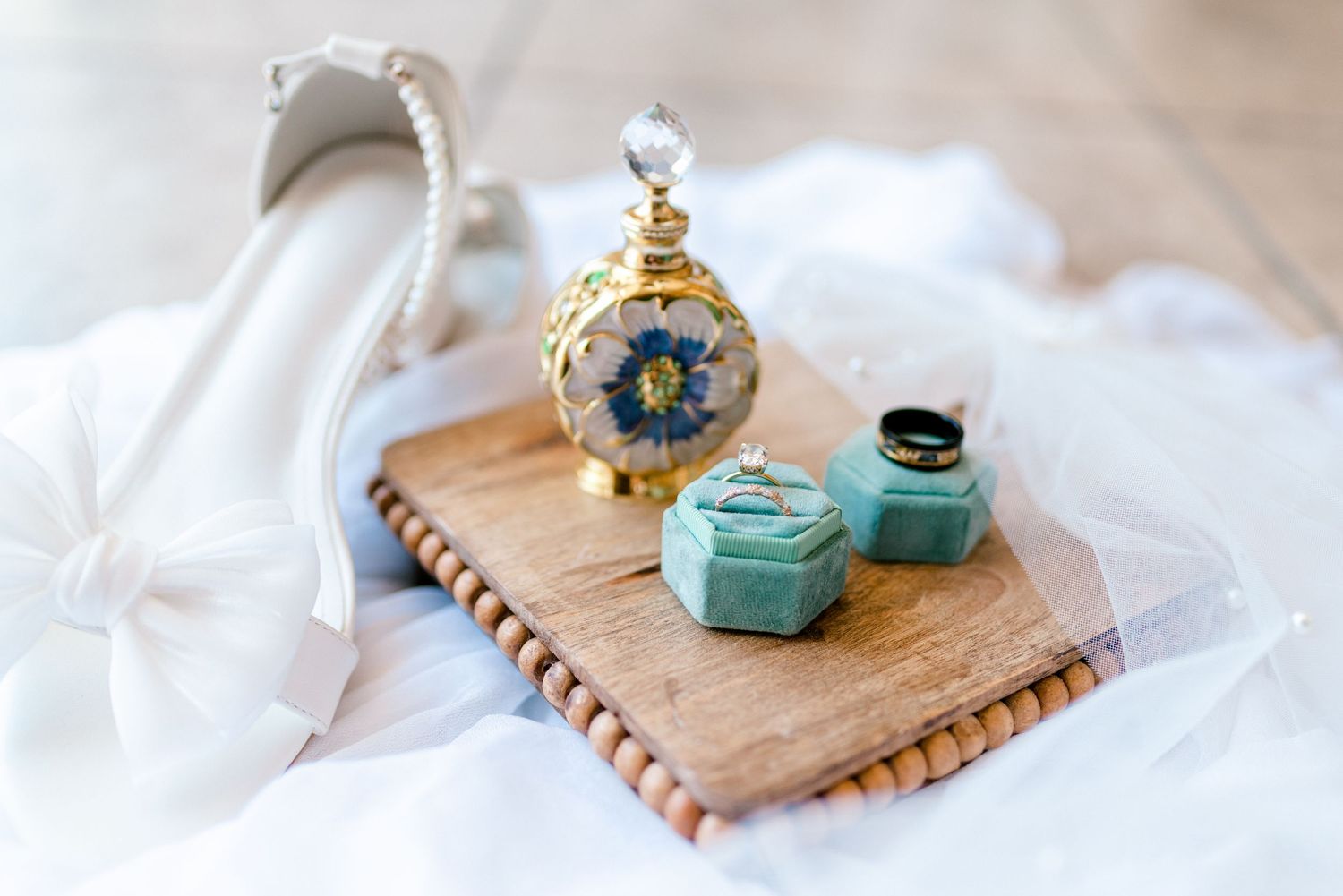 Wedding details featuring vintage books, blue glass bottle and decorative items on white fabric.