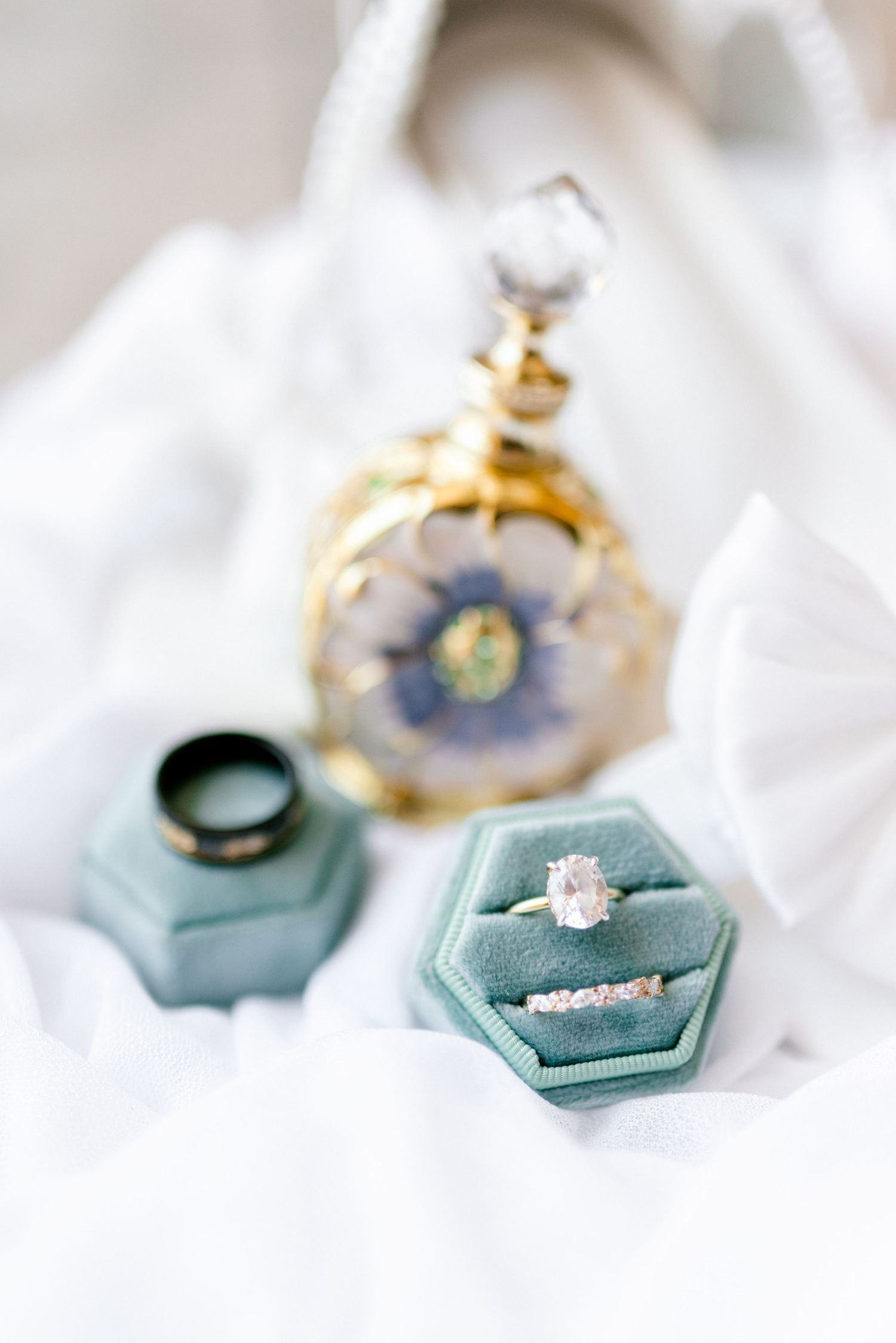 Elegant engagement ring displayed on mint green velvet ring box with soft white fabric background.